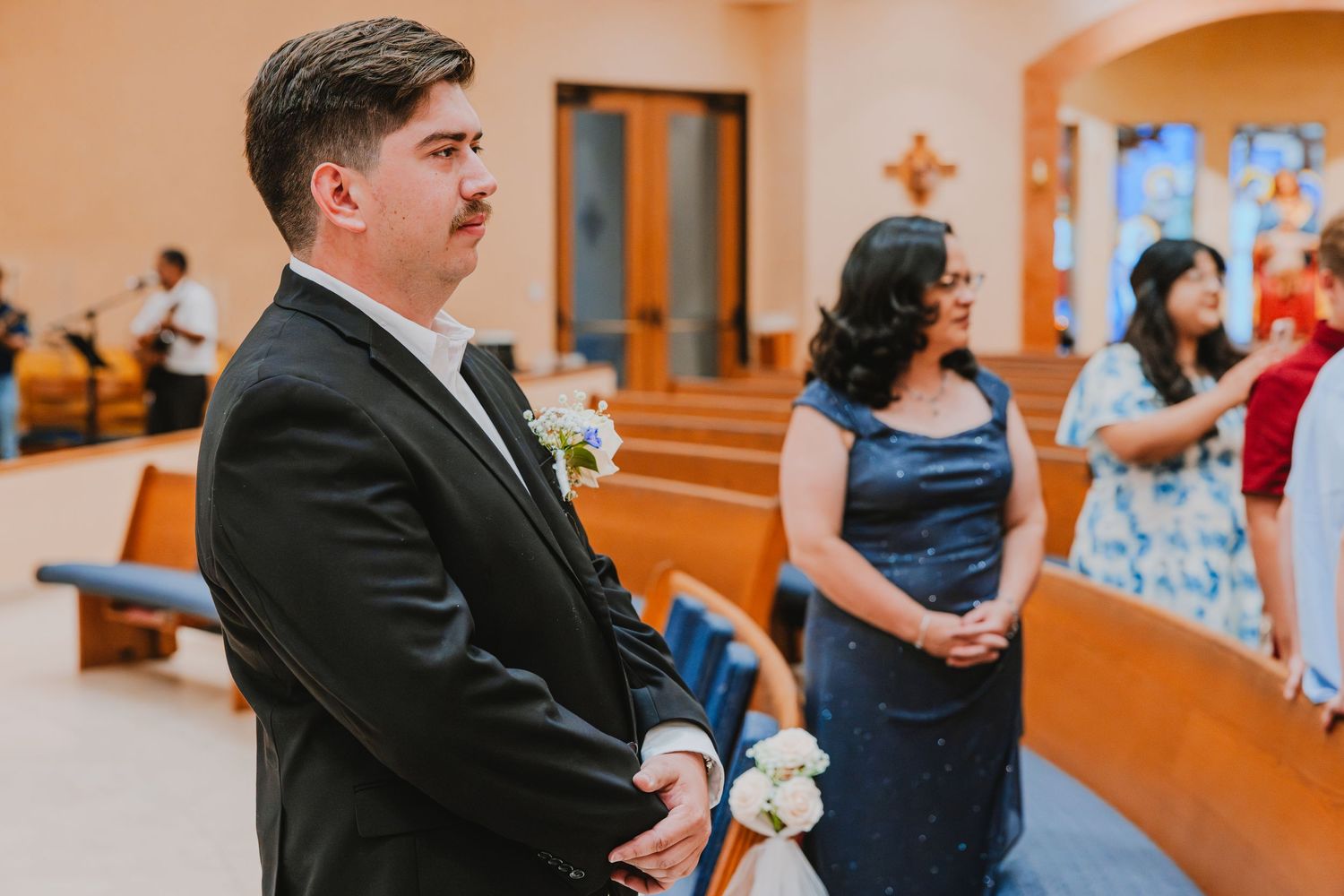 A bride and groom share their first dance in an elegant ballroom with orange-tinted lighting and guests watching.