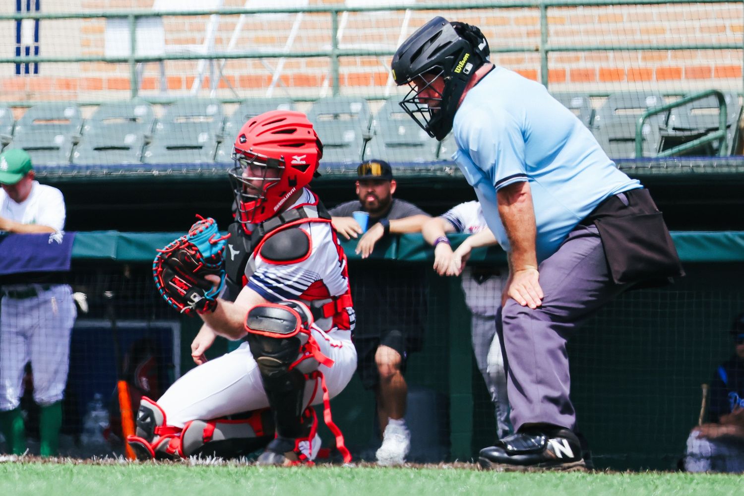 Baseball catcher crouches behind home plate in protective gear during a game at a professional stadium.