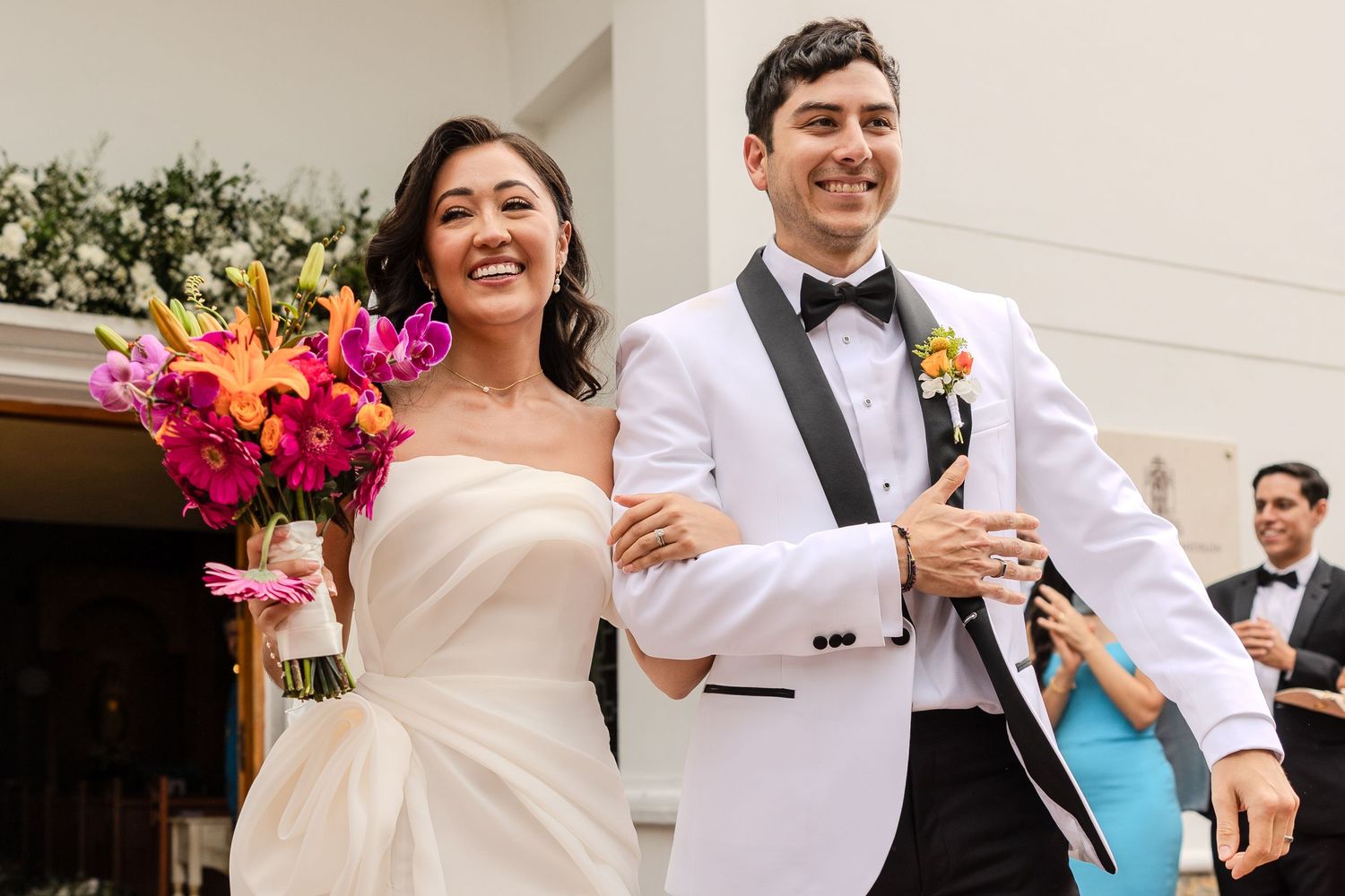 Joyful couple dancing together at their wedding celebration with colorful floral arrangements.
