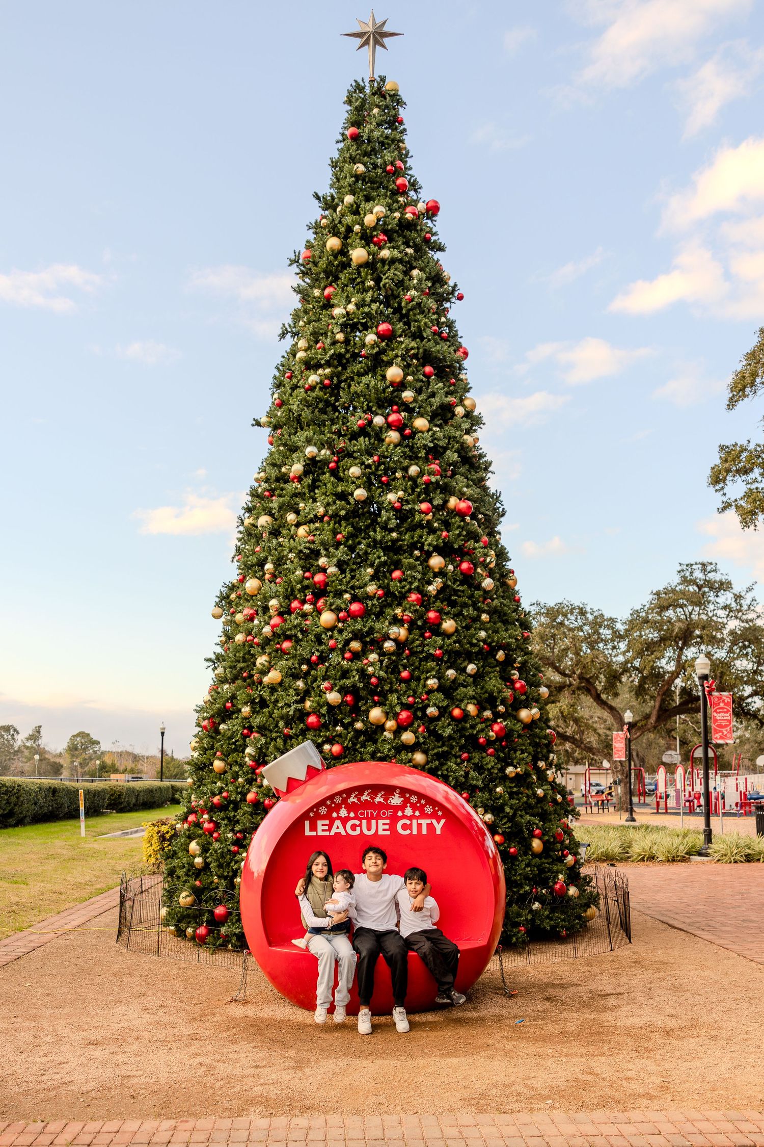 Holiday scene with large decorated Christmas tree and red bench in League City.