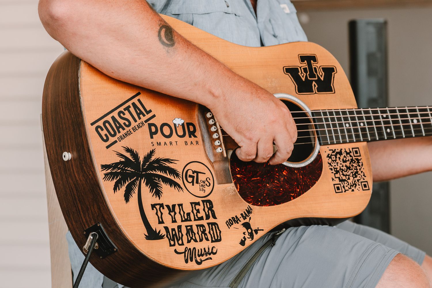Wooden ukulele decorated with hand-drawn palm trees, text, and artistic designs on its natural wood surface.