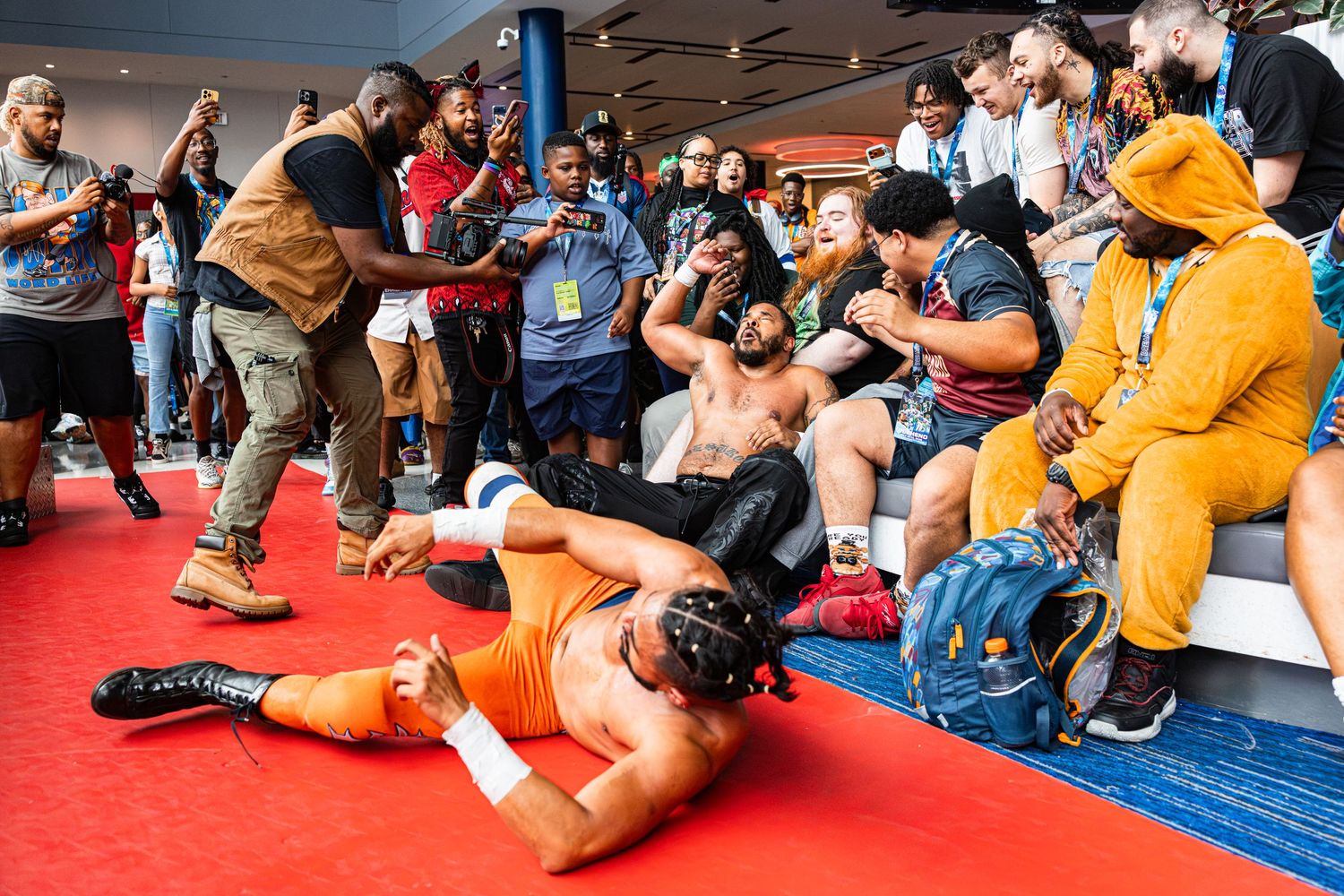 Wrestlers perform in front of an excited crowd at an indoor wrestling event with fans watching closely.