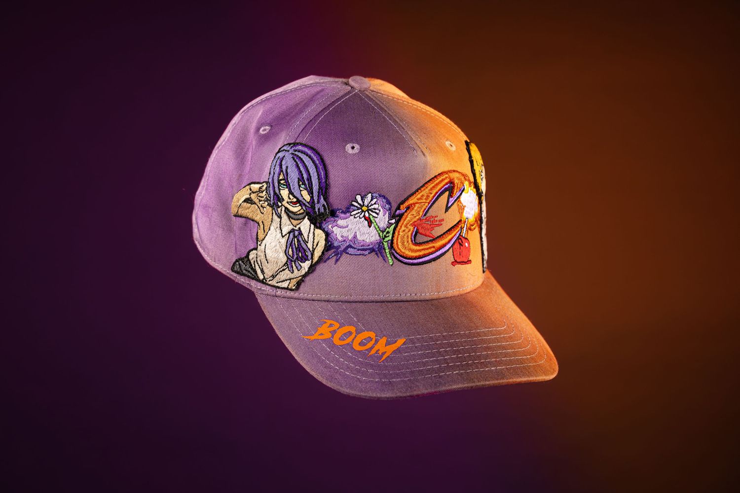 Purple snapback cap with cartoon character artwork and orange BOOM embroidery on gradient dark background.