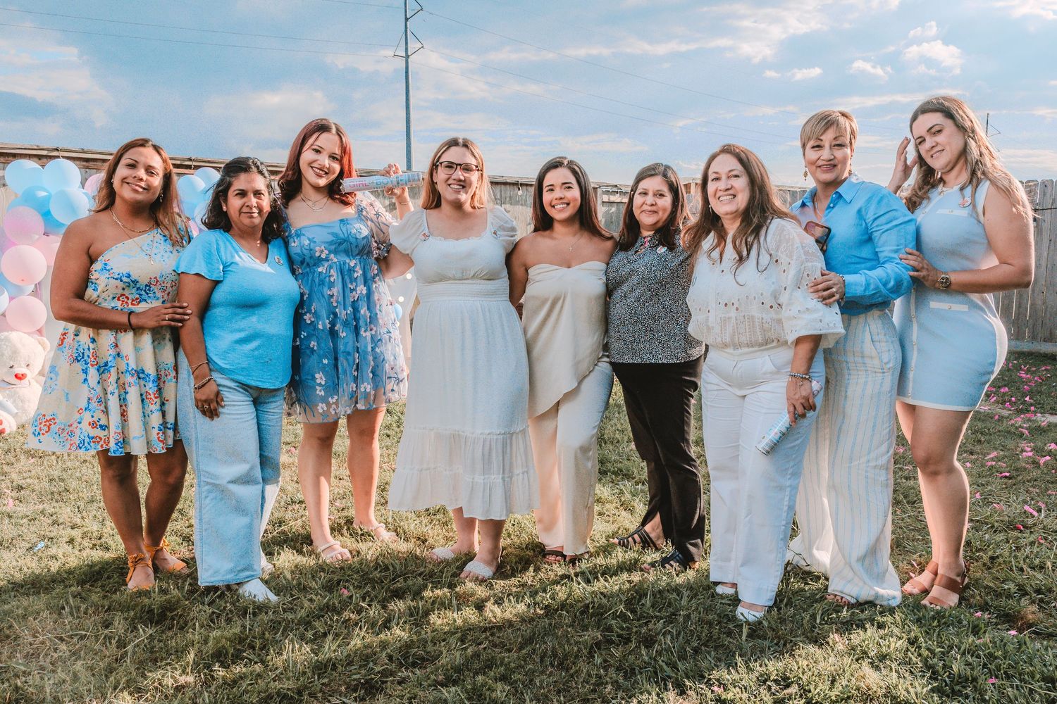 Group wearing coordinated blue and white outfits poses together outdoors during sunset.