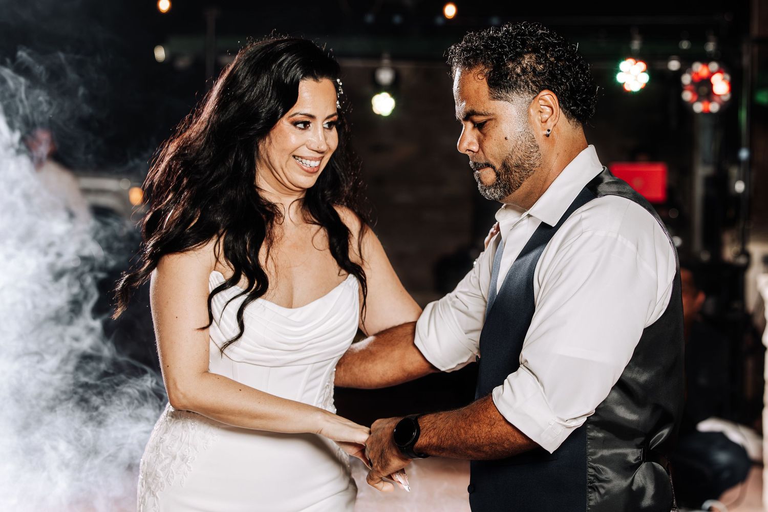 A couple dances together in a romantic setting with soft lighting and fog effects creating an ethereal atmosphere.