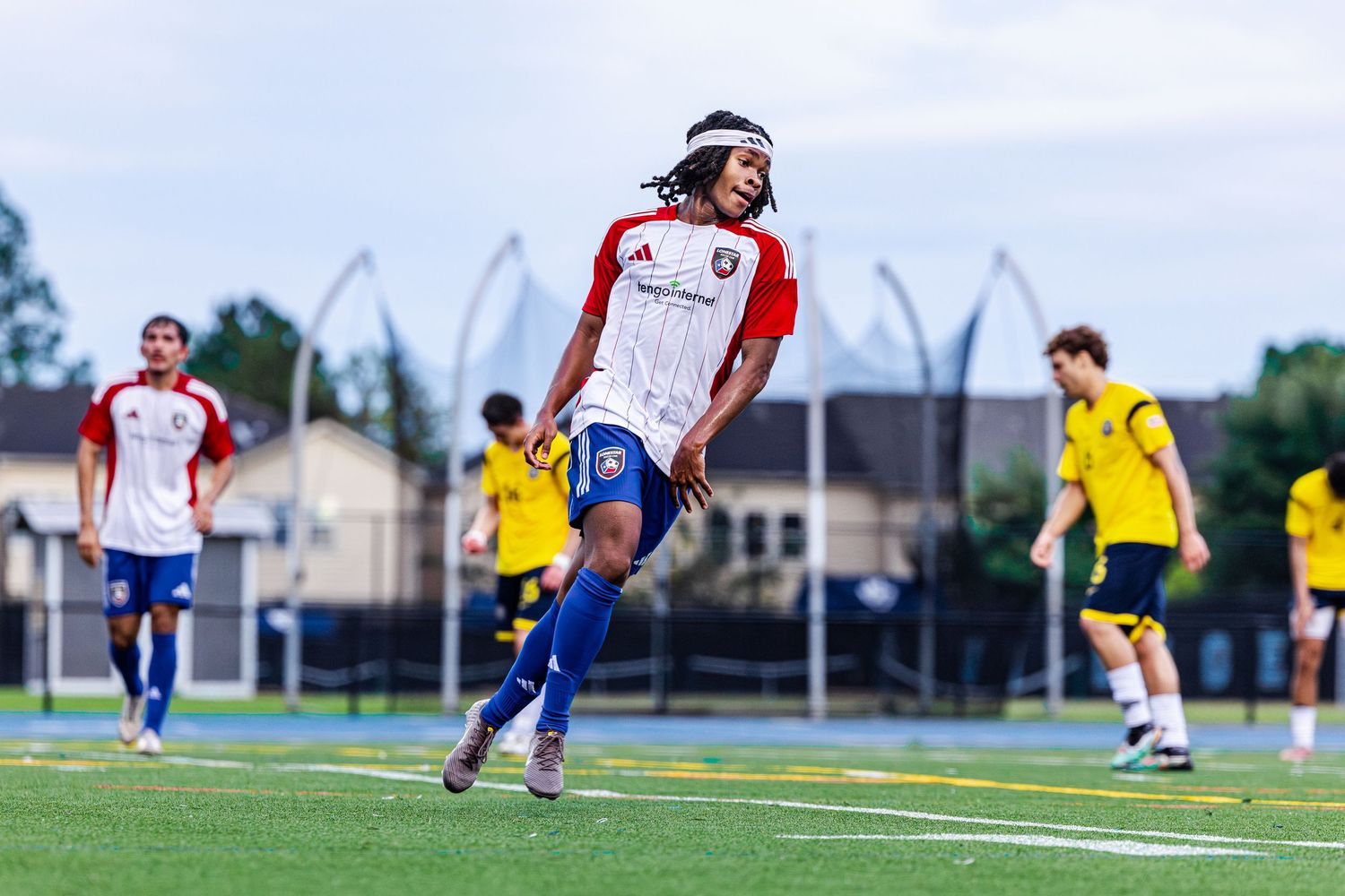 Soccer player in red and white jersey celebrates on green field during a youth soccer match.