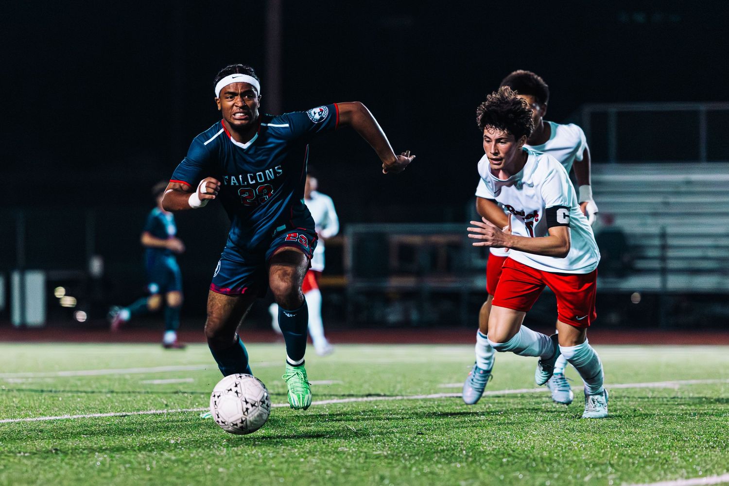Soccer players compete for possession of the ball during an intense match on a grass field.
