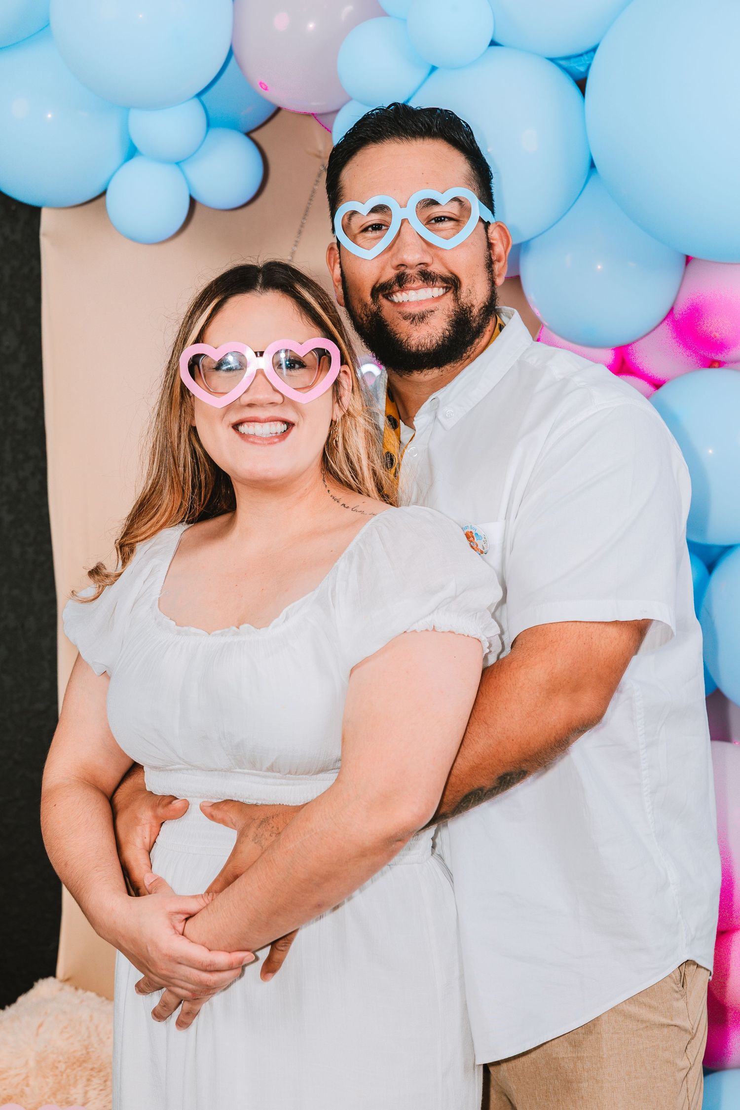 Couple poses playfully with blue and pink balloon decorations in a series of casual celebration photos.