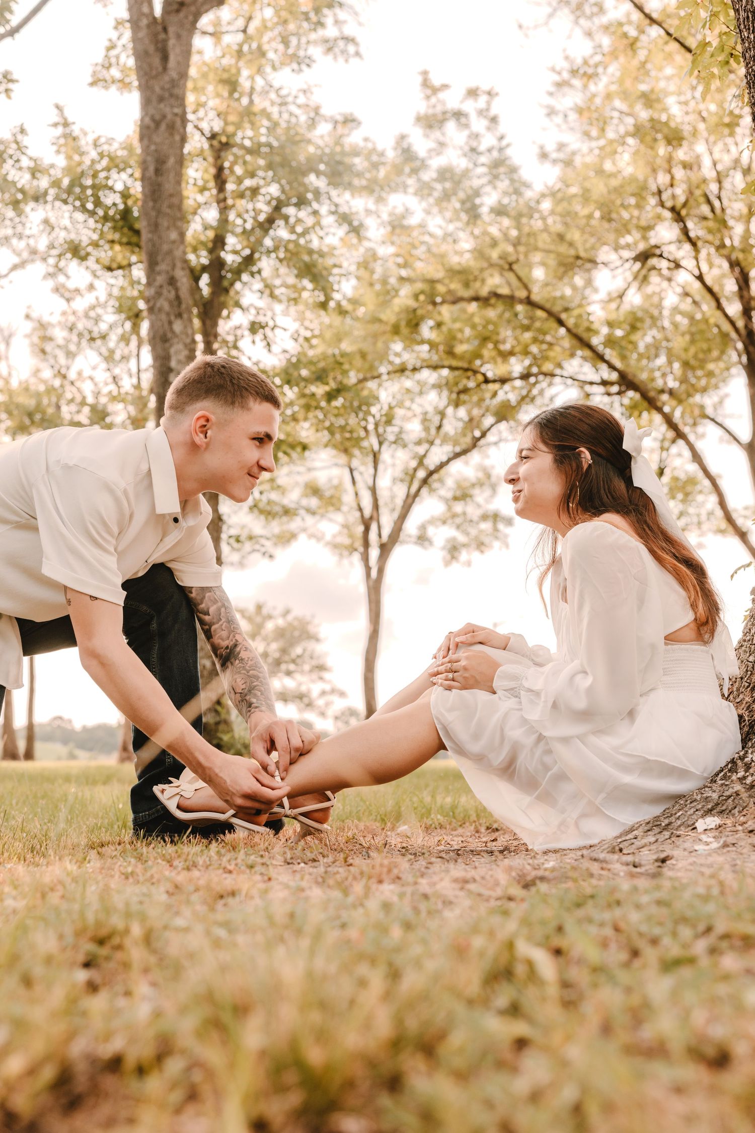 Romantic couple in white outfits lying on autumn grass in a series of candid poses during sunset photo session.