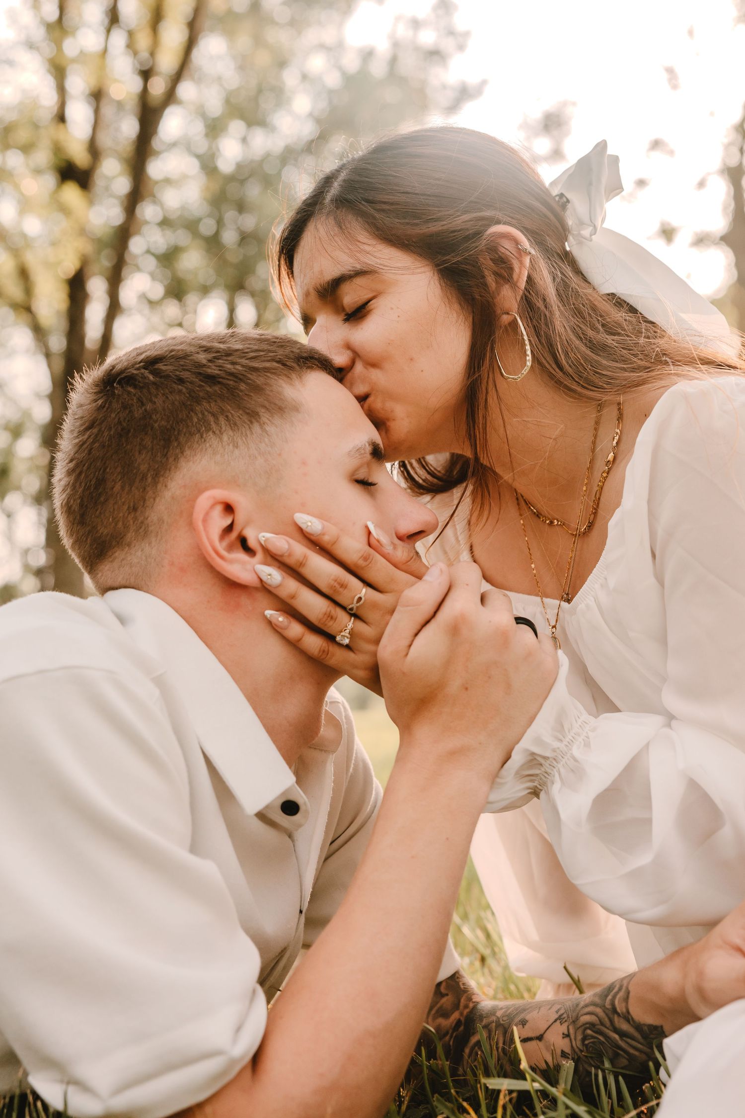 Intimate couple's portrait session in natural lighting with white clothing against forest backdrop.