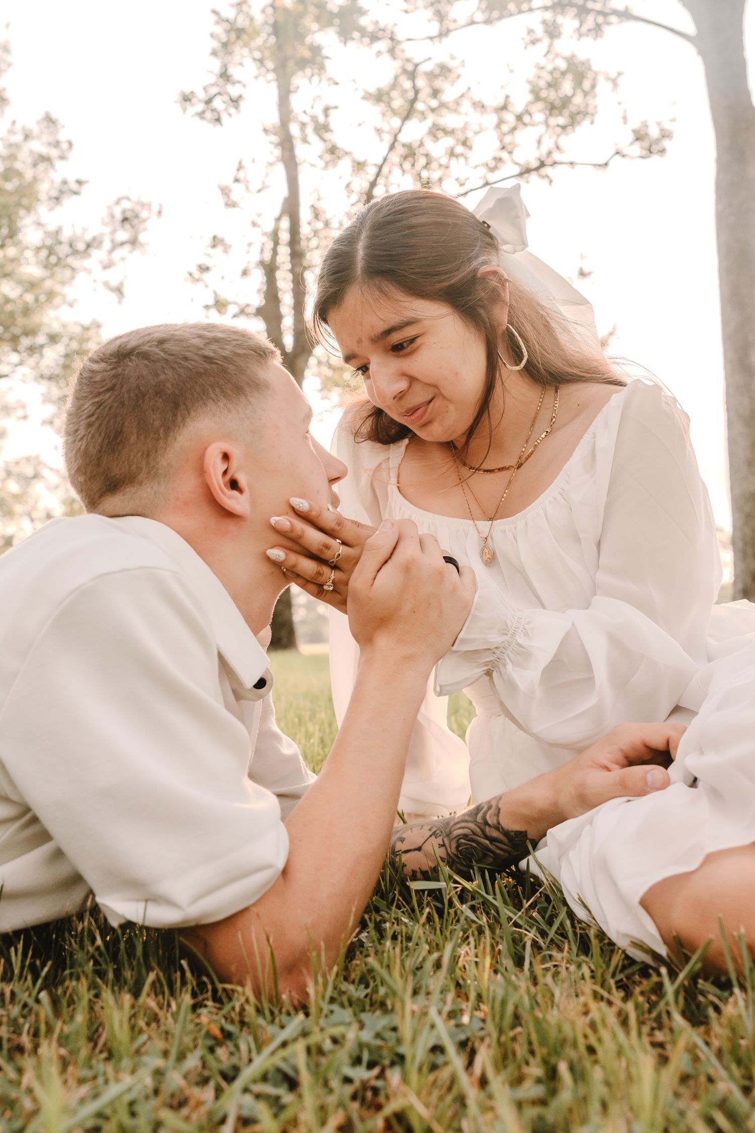 Intimate couple lying in grass during golden hour outdoor photography session.