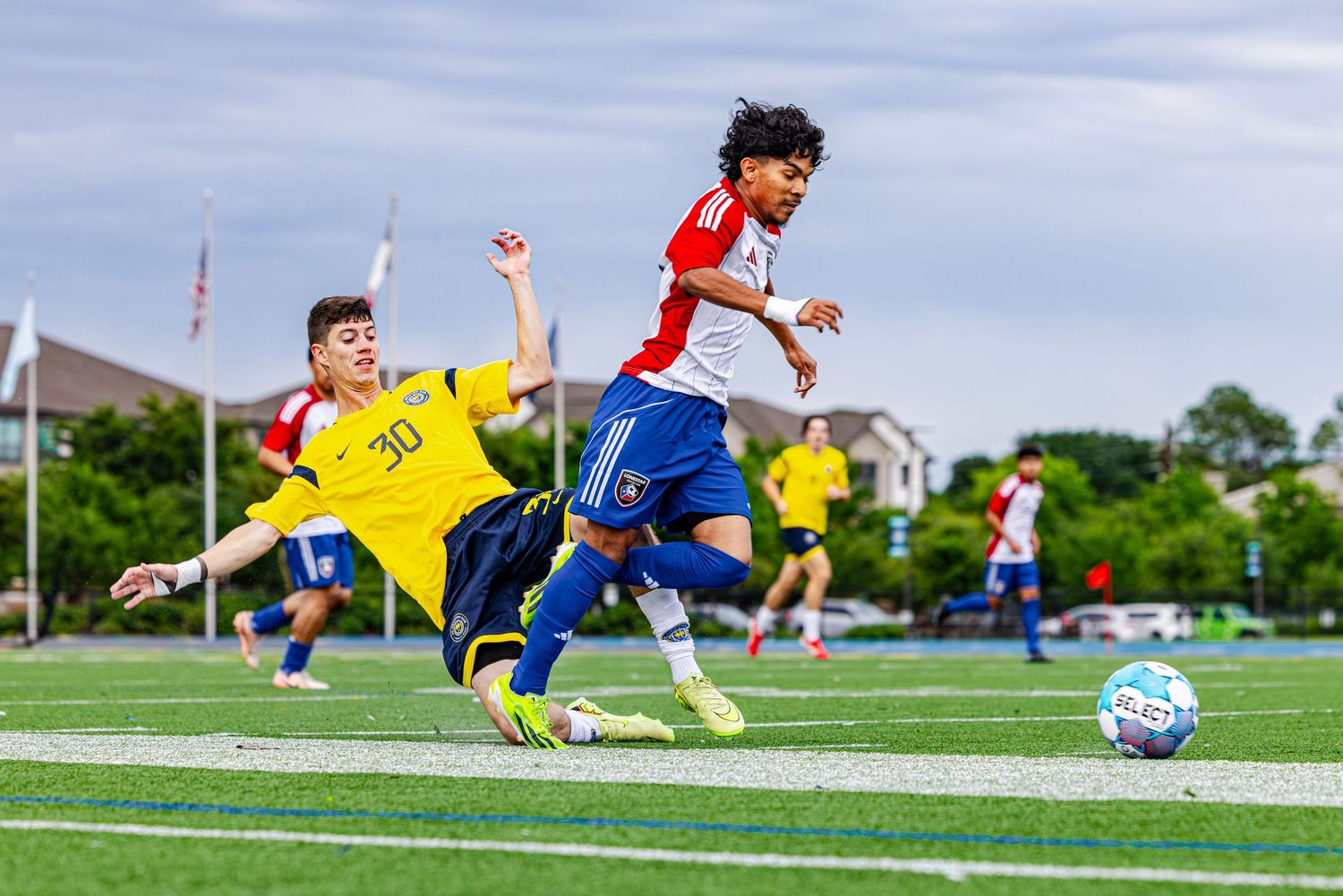Two youth soccer players compete for the ball during a match on a green turf field.