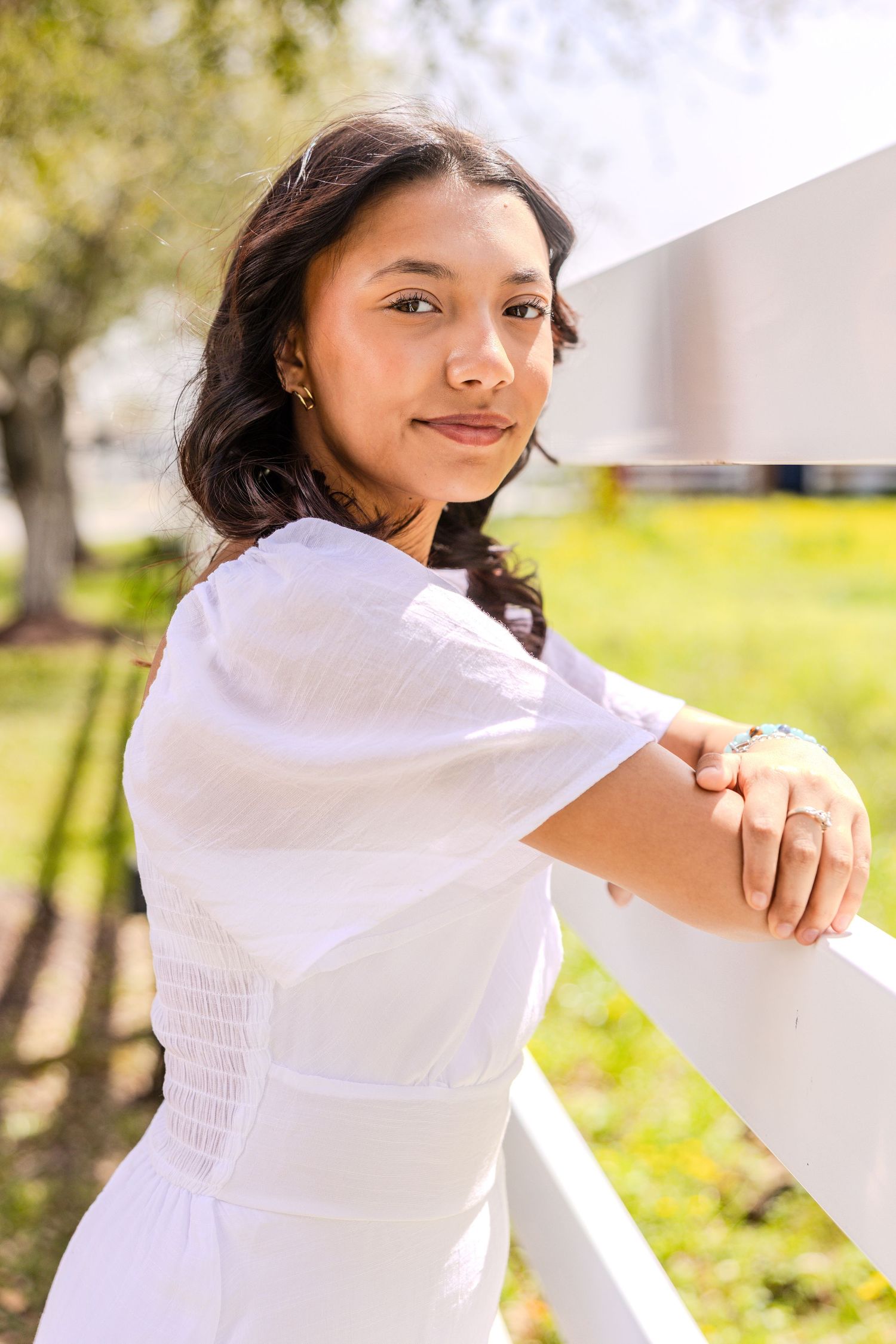 Person in white twirling joyfully in sunlit outdoor setting.