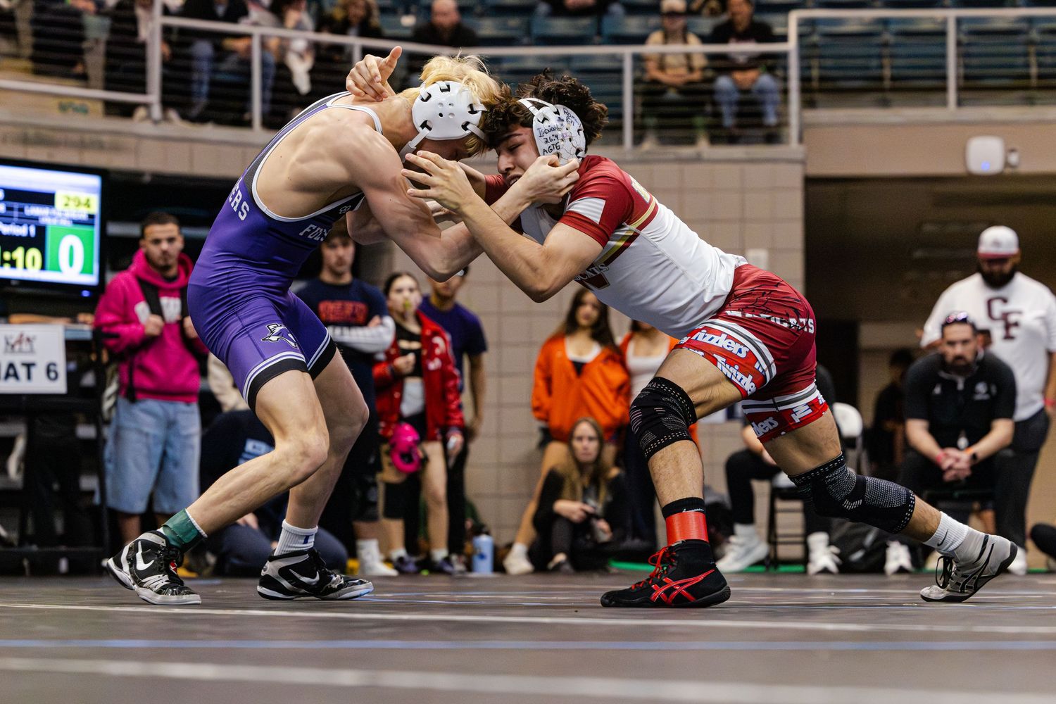 Two wrestlers compete in an intense match on a mat during a competitive wrestling tournament.