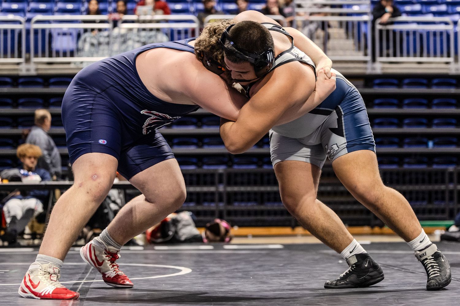 Wrestling competitors in action during match on blue competition mat.