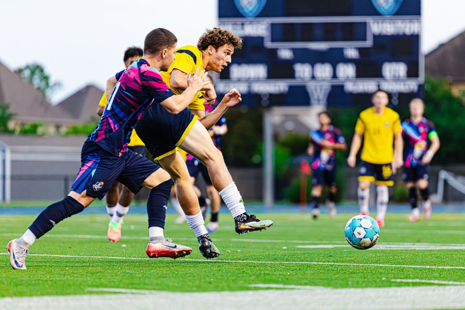 Soccer players compete for the ball during an intense match on a well-lit outdoor field at night.
