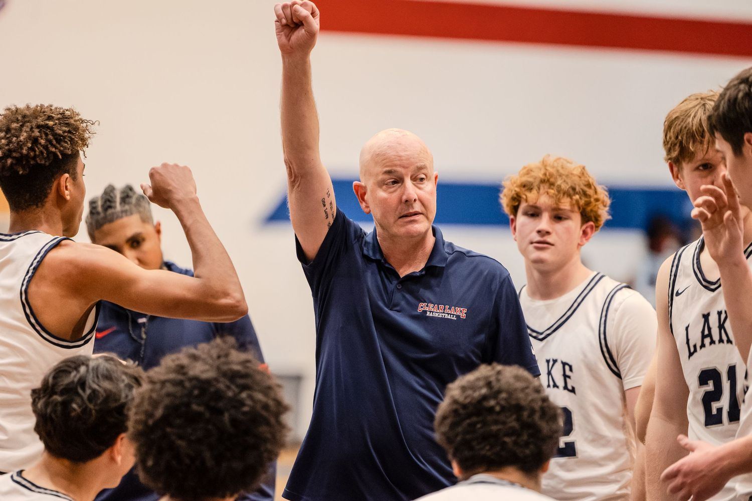 Basketball players celebrate during an intense game with teammates and coaches showing excitement on the sidelines.