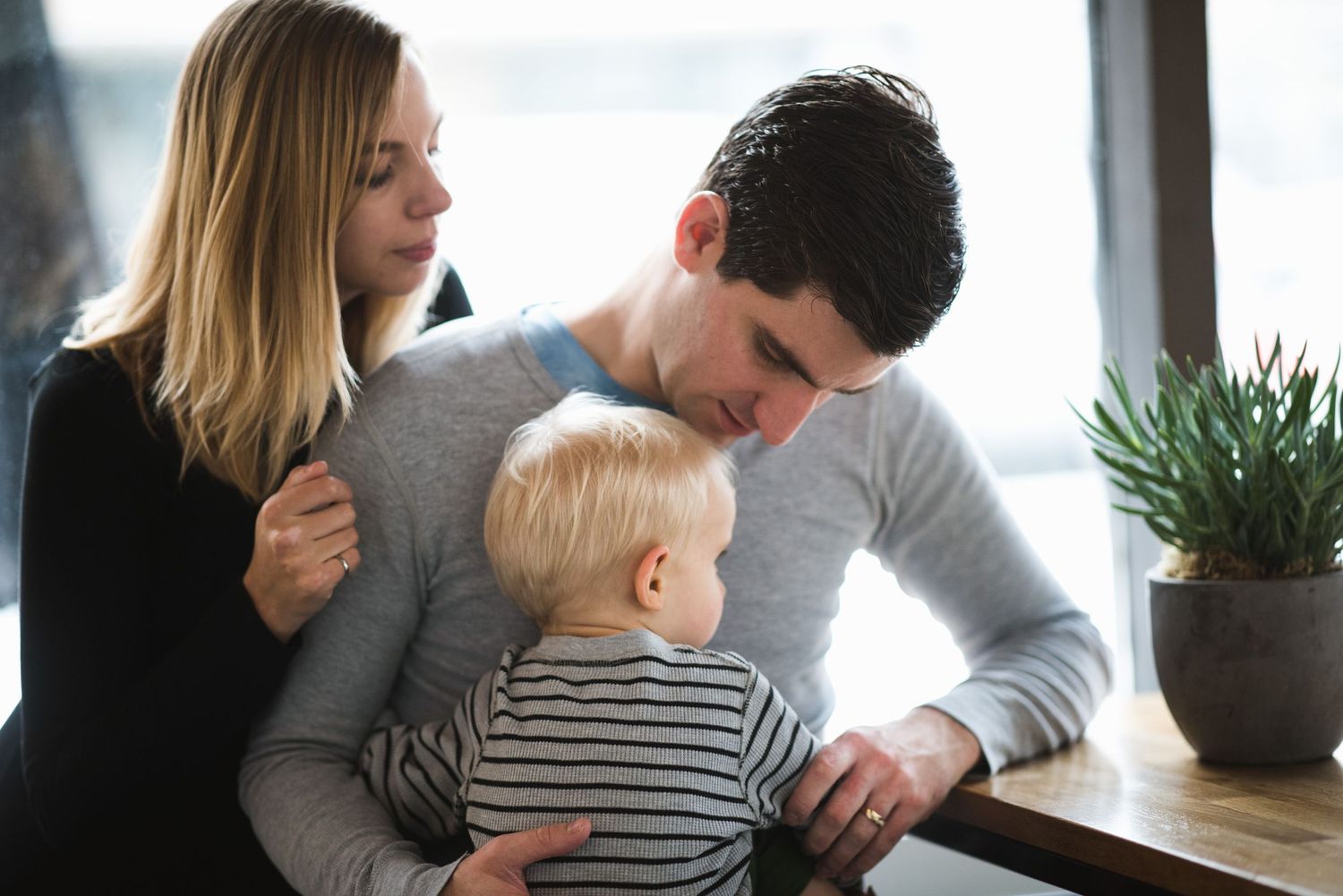 Calgary family snuggled by the window. Honest indoor lifestyle moment with natural light and connection.