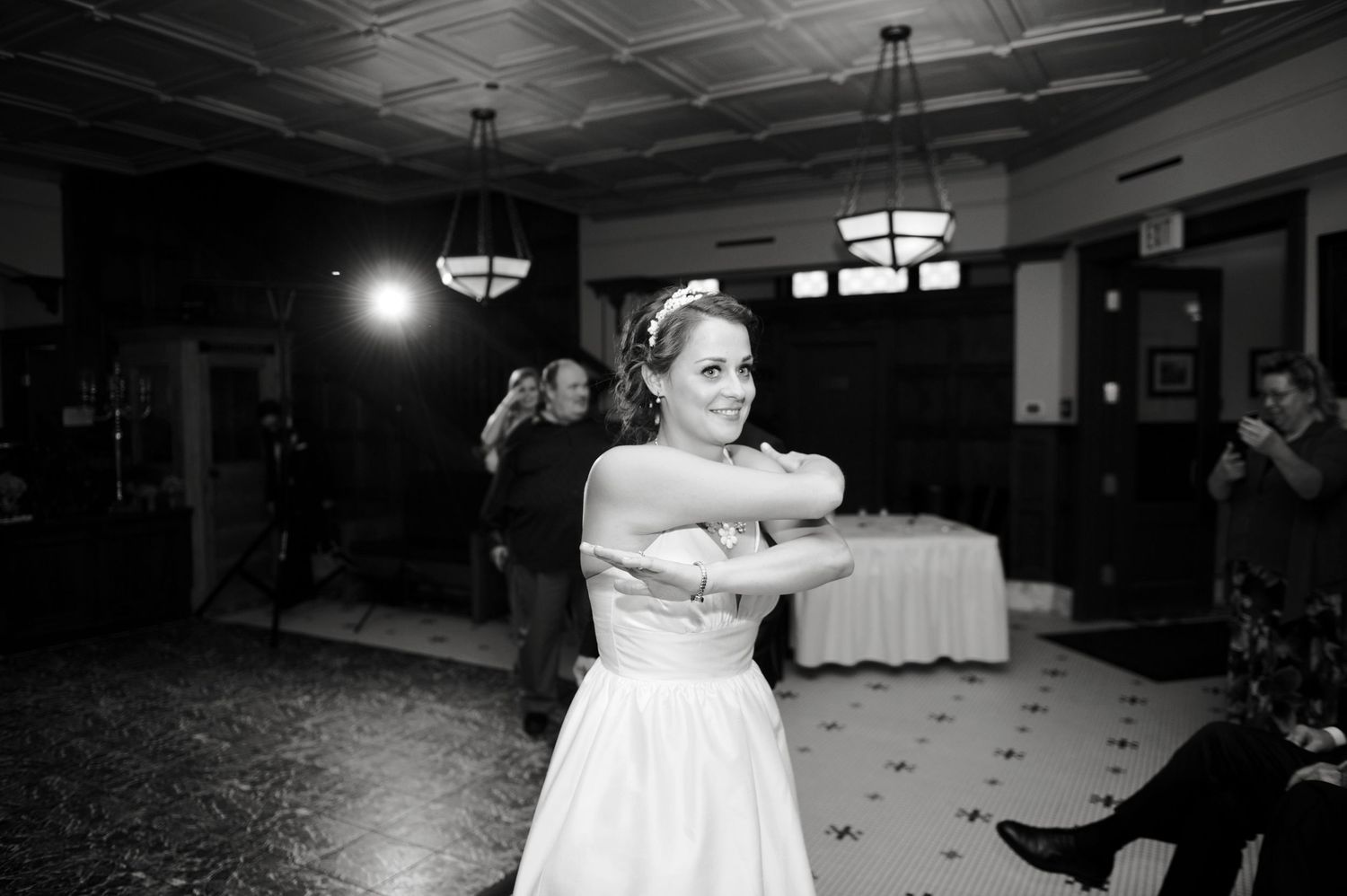 Black-and-white photo of a smiling bride mid-spin on the dance floor during a wedding reception.