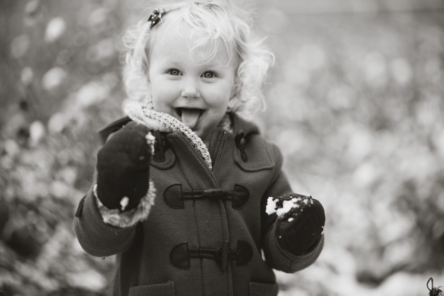 young toddler girl playing in the snow and smiling at the camera