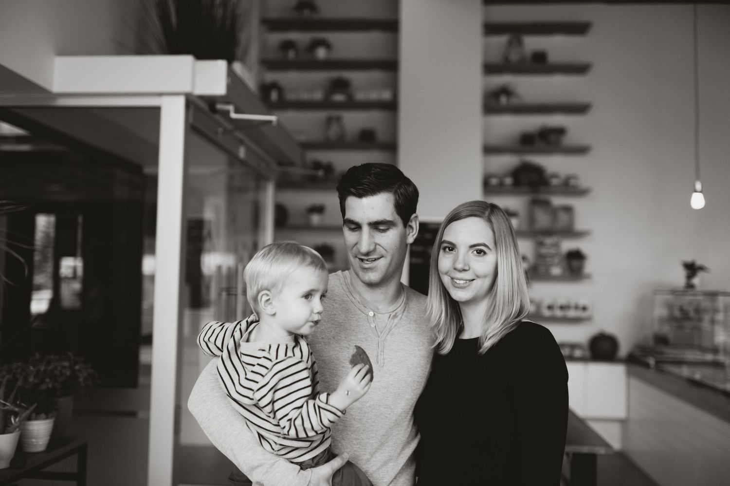 Candid black and white family portrait inside a Calgary café. Warm indoor storytelling with kids.