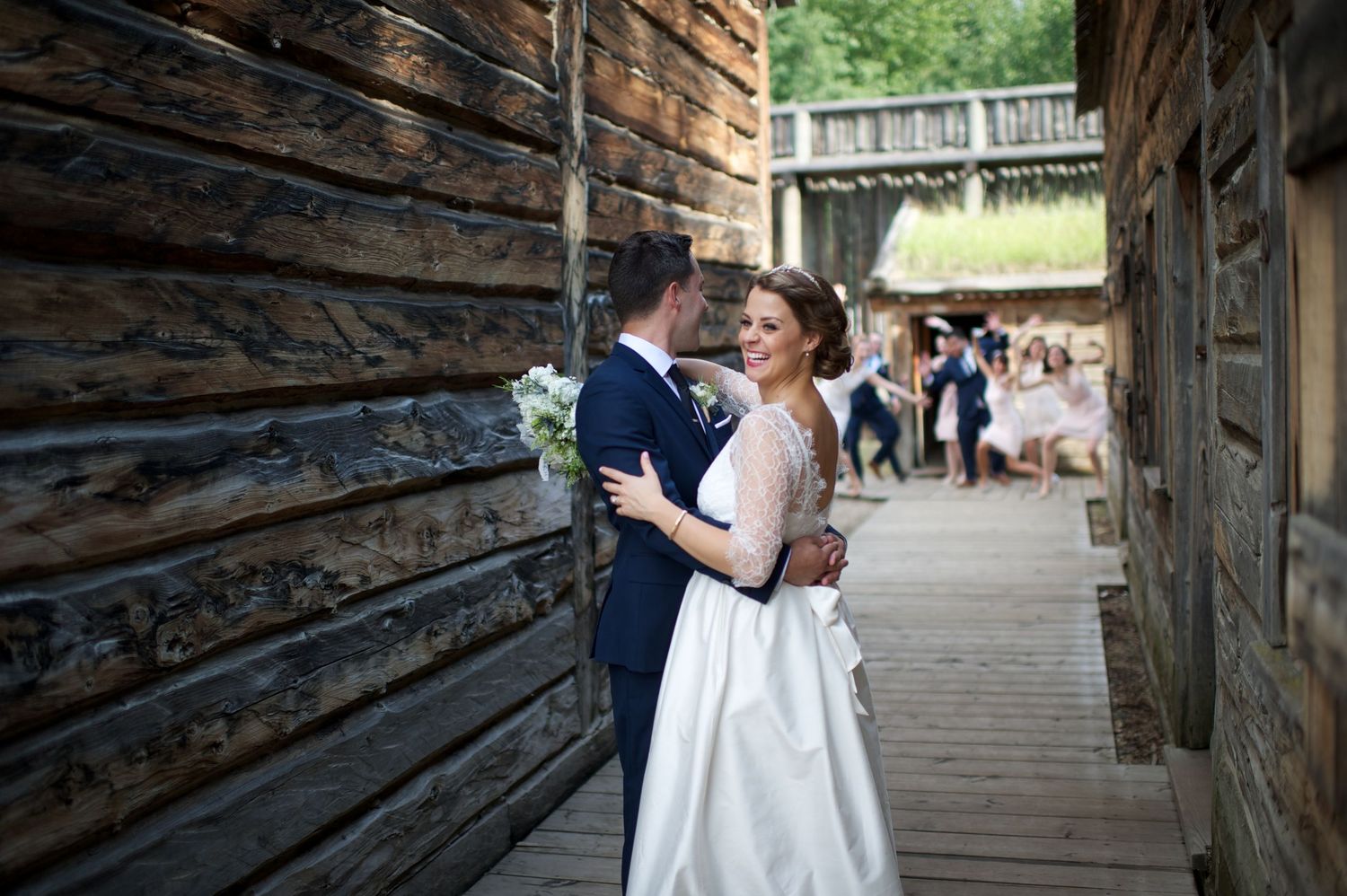 Bride and groom smiling together, leaning into one another in a rustic village path.