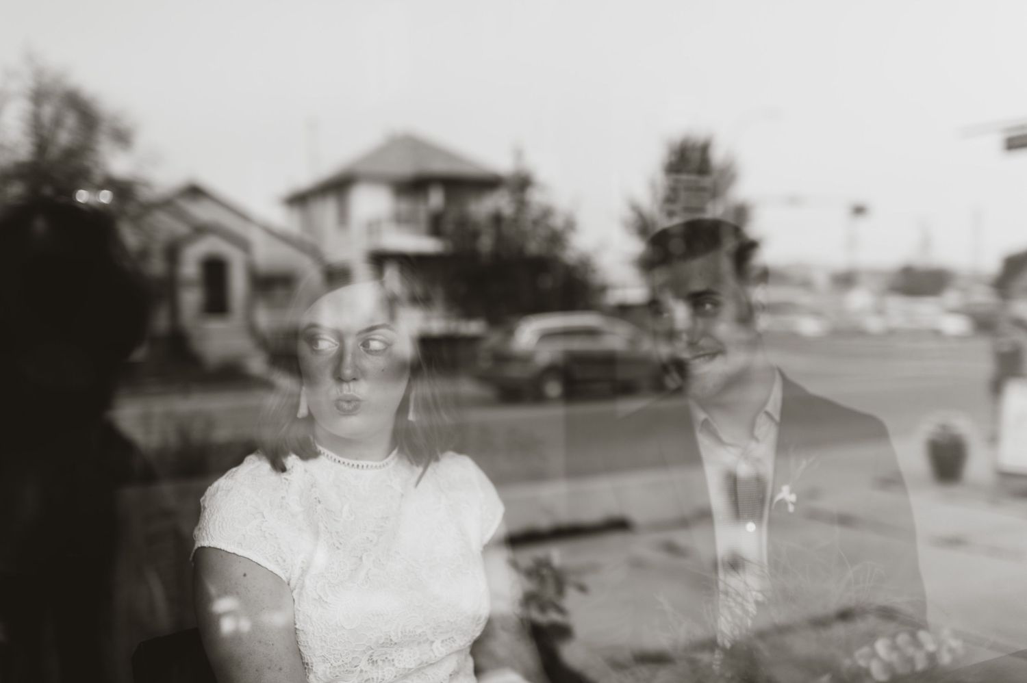 Artistic window reflection of bride and groom during city elopement. Black and white candid wedding portrait.