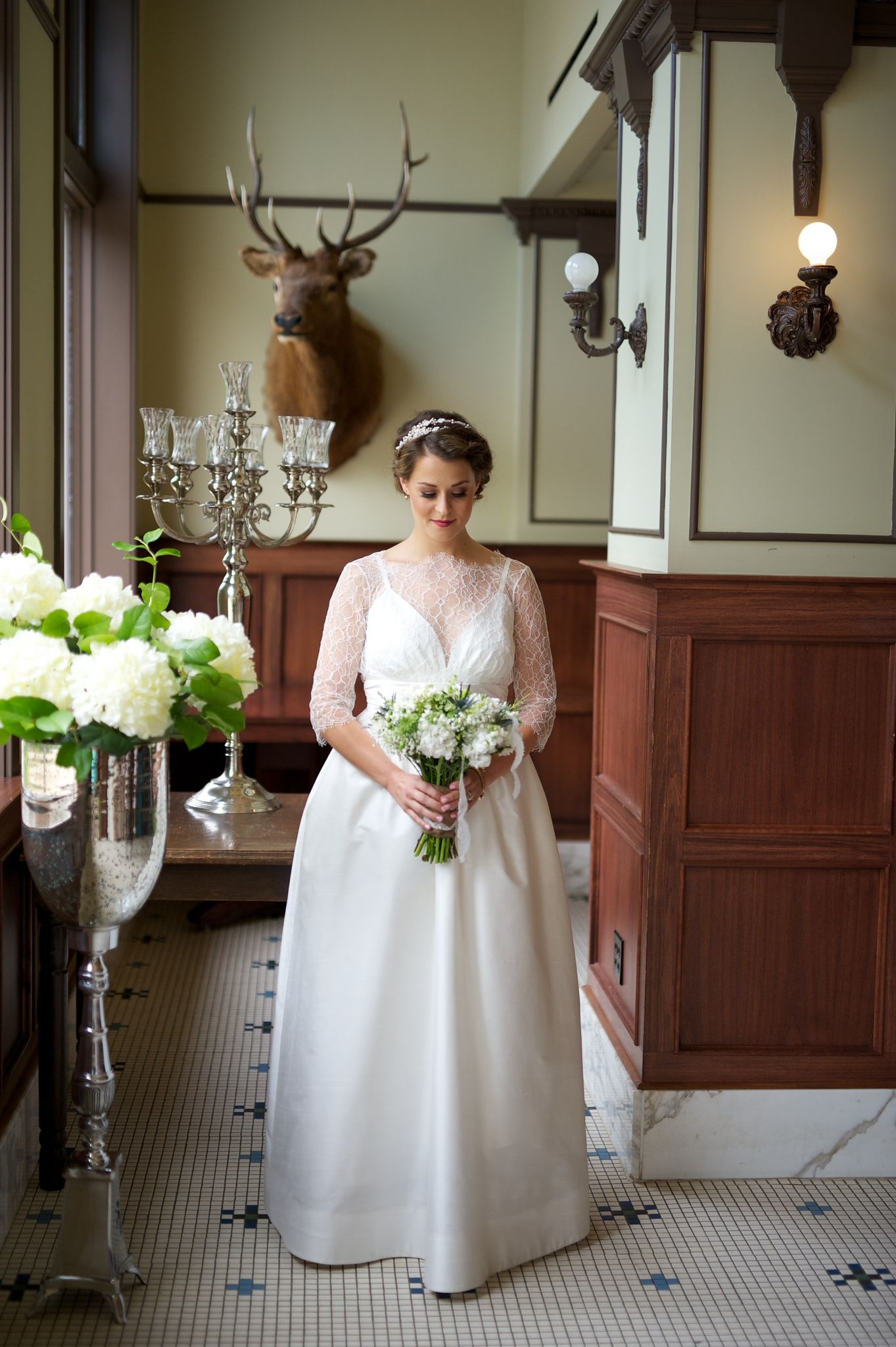 Full-length bridal portrait in a vintage room. Her calm presence and classic gown set a timeless mood.