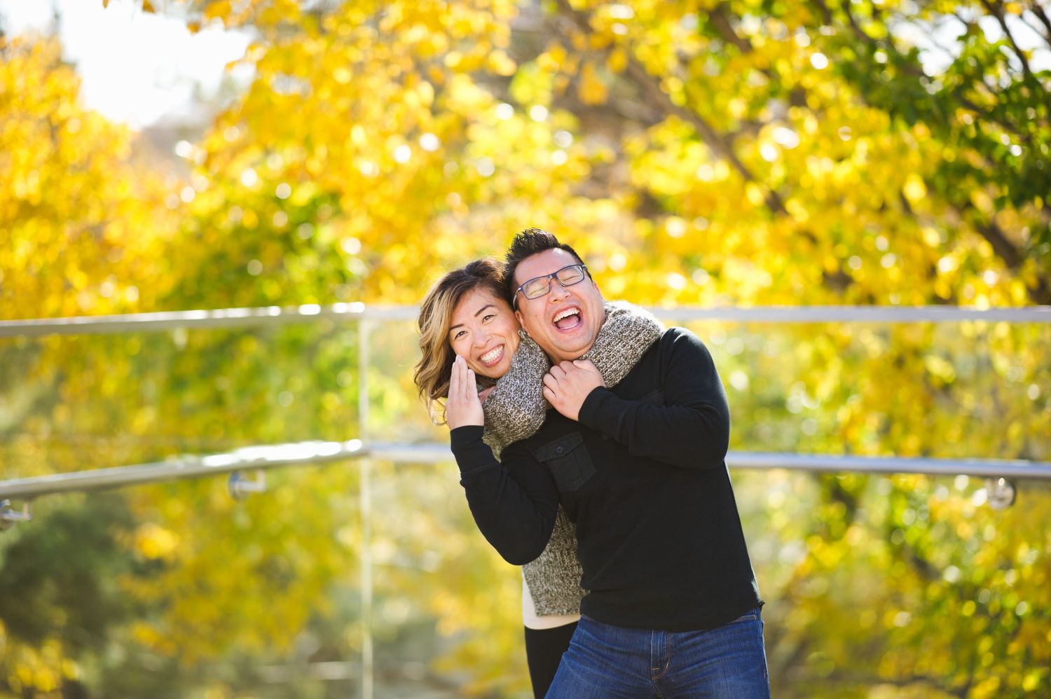 Couple laughing as one playfully holds the other in a headlock, trees glowing behind them.