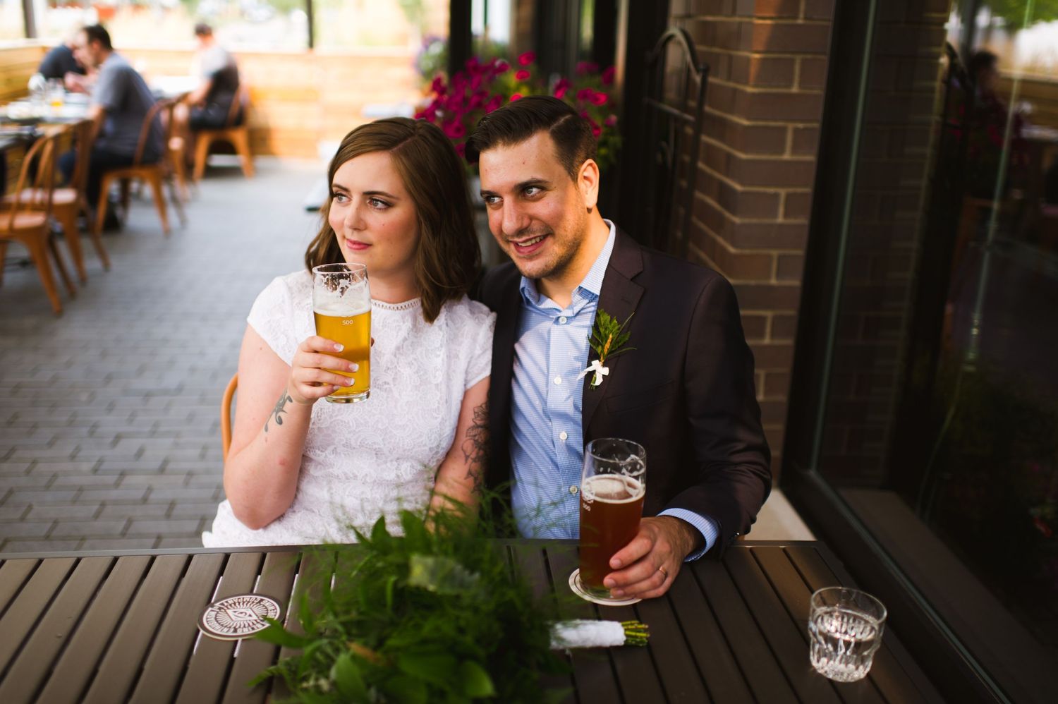 Bride and groom share craft beers on brewery patio after their Alberta elopement. Relaxed, modern wedding celebration.