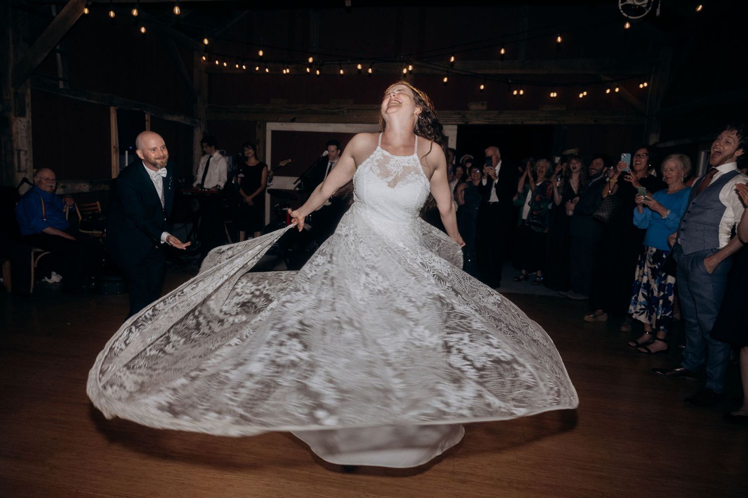 A couple dancing together at their wedding reception on a dark dance floor with twinkle lights overhead.
