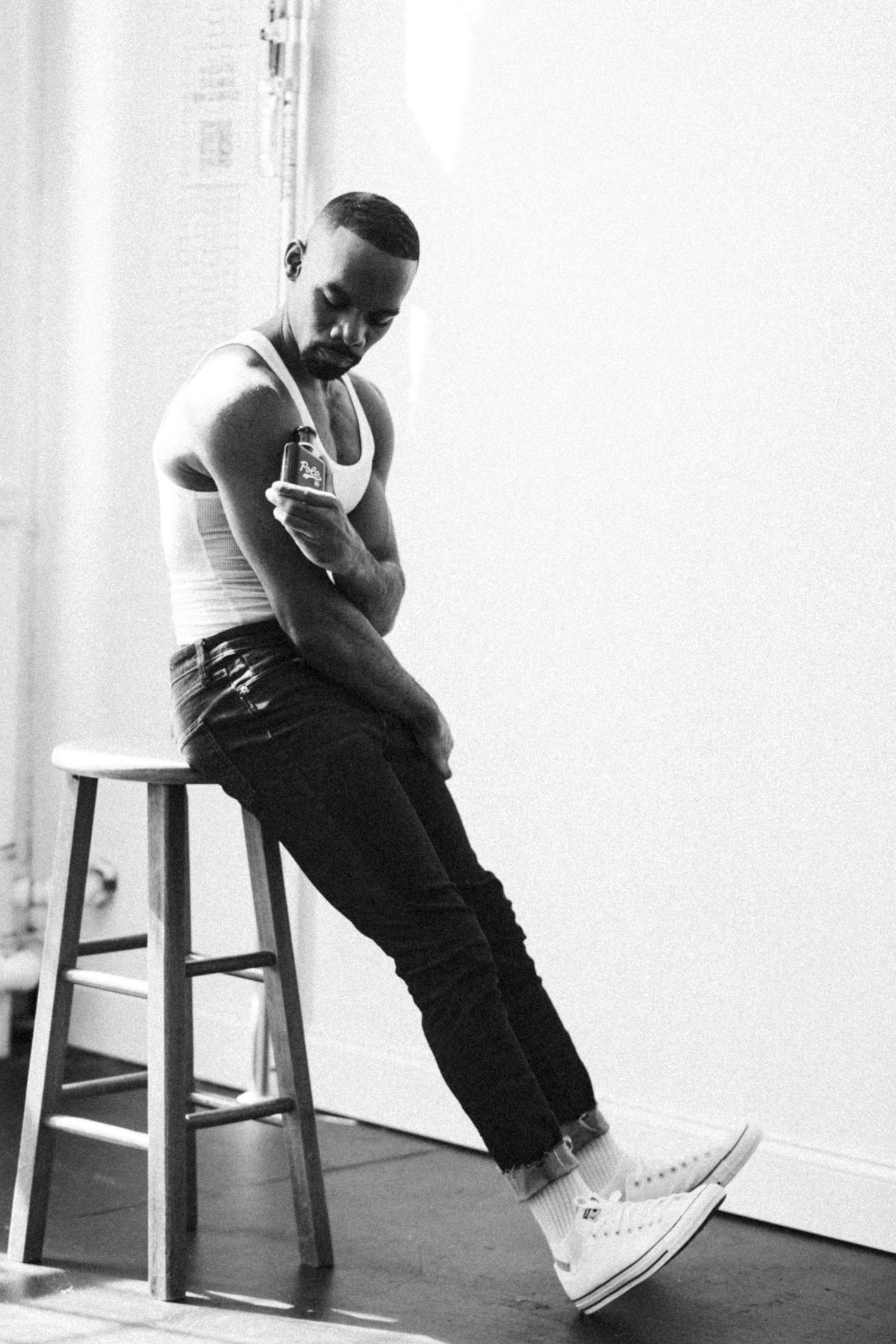 Monochromatic portrait series showing contemplative poses on wooden stool against white wall.