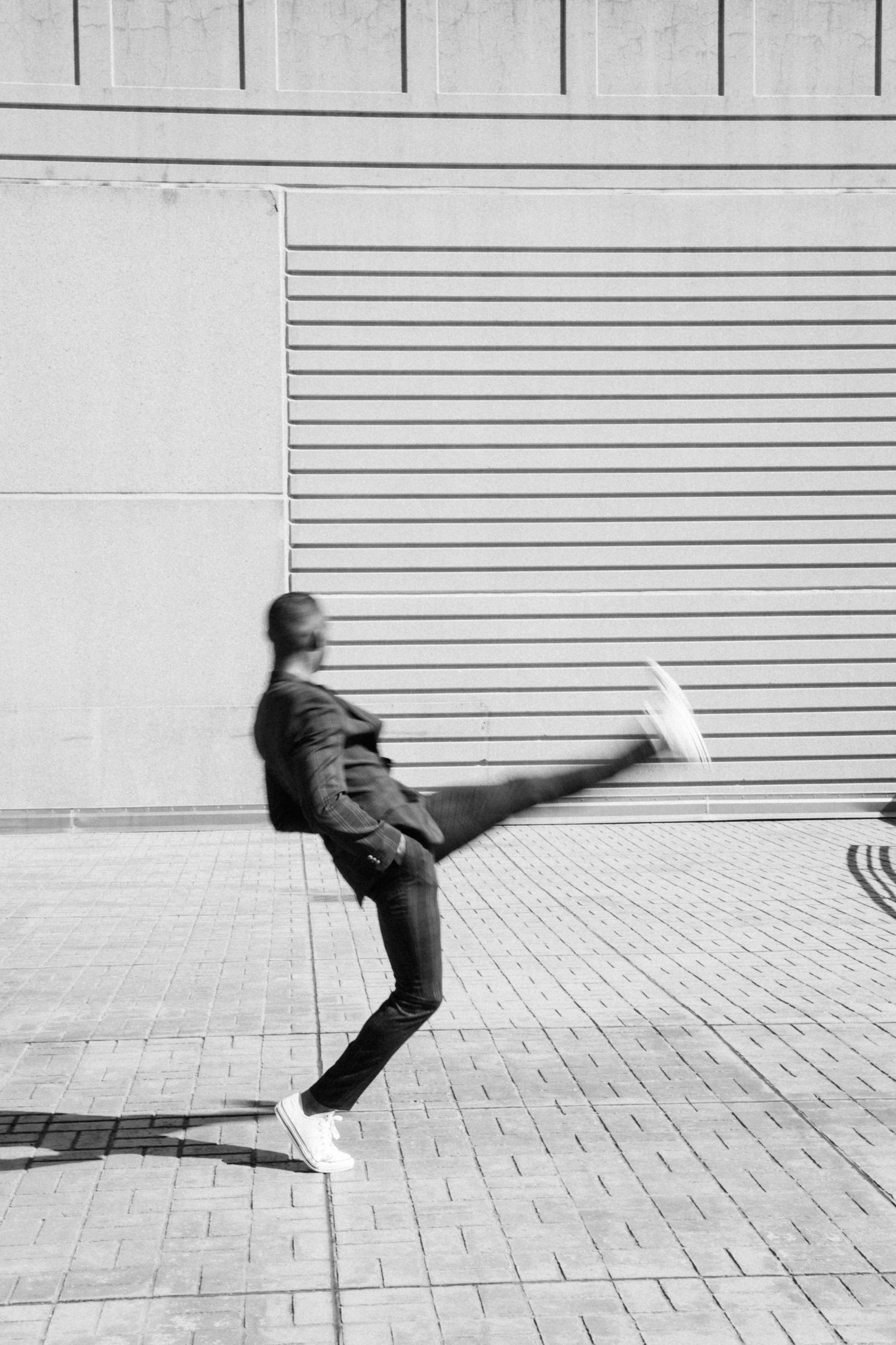 Black and white sequence showing movement and dance against an urban wall backdrop.