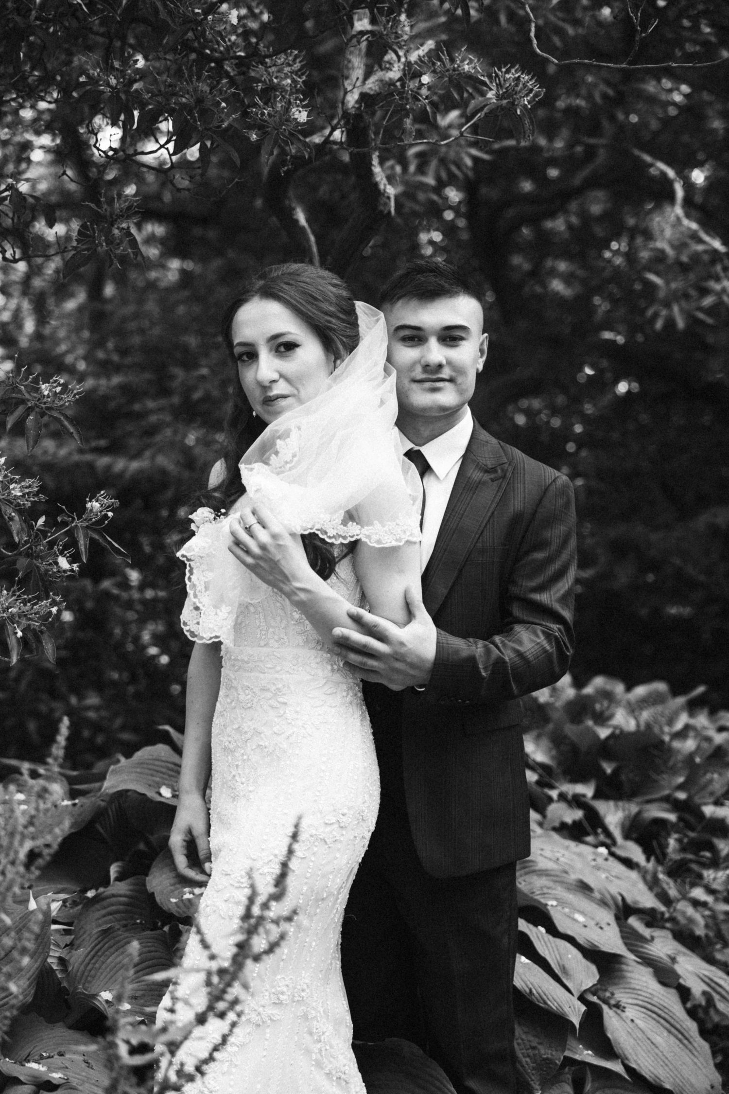 Wedding portraits captured in a natural garden setting with lush foliage.
