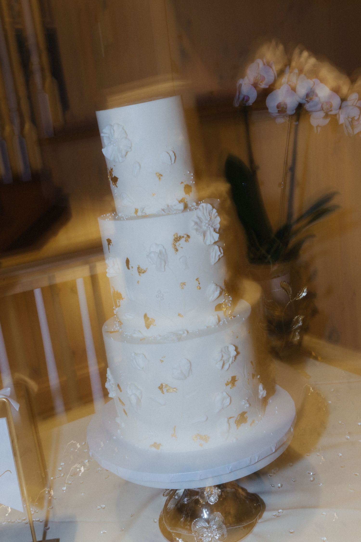 Elegant white tiered wedding cake decorated with delicate gold accents.