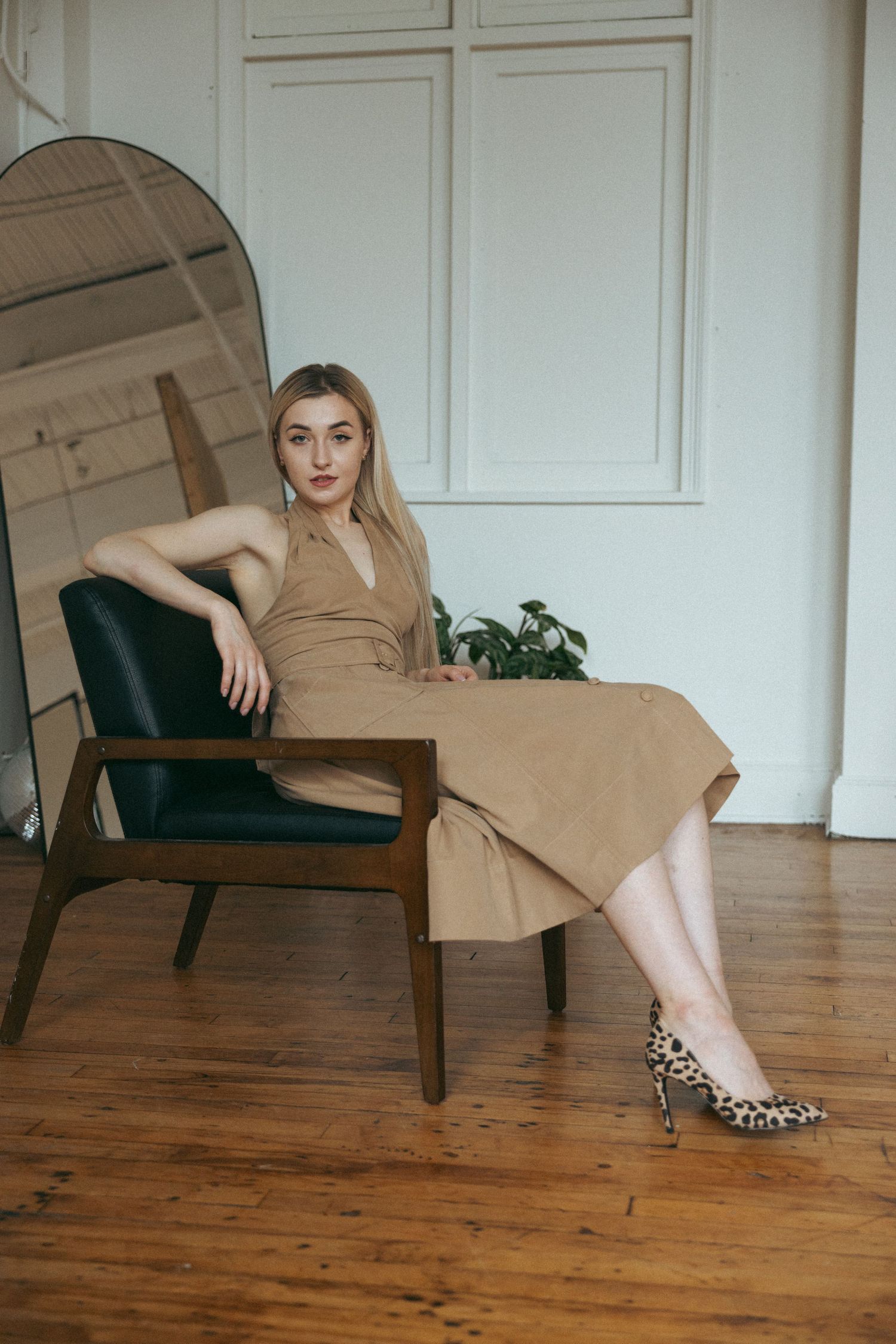 Fashion poses on wooden floor featuring tan outfit and leopard print shoes.