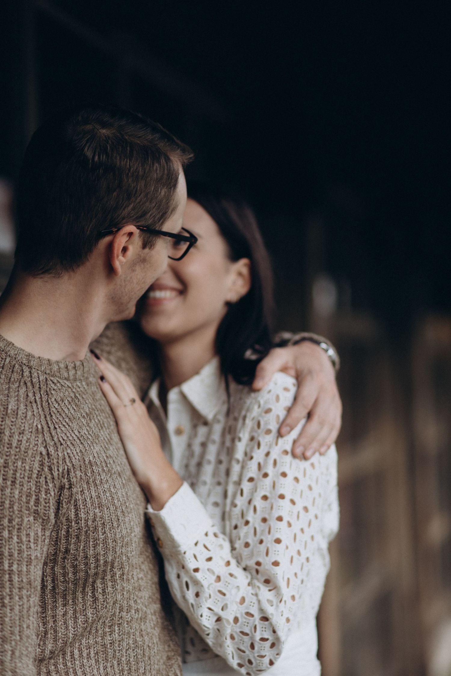 A tender moment shared between a couple wearing cozy knitwear against a dark backdrop.