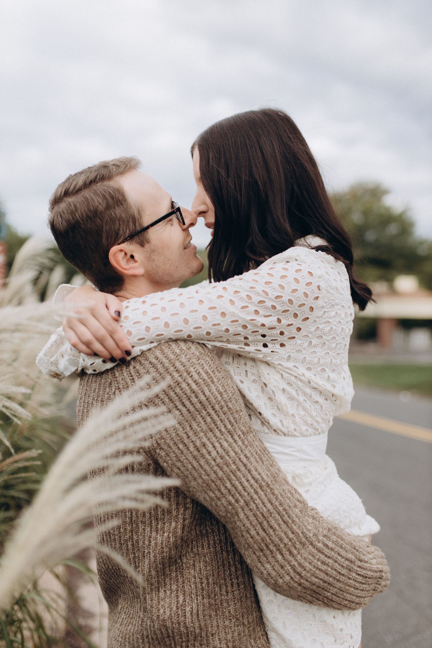 Couple sharing an embrace outdoors in fall sweaters and casual attire.