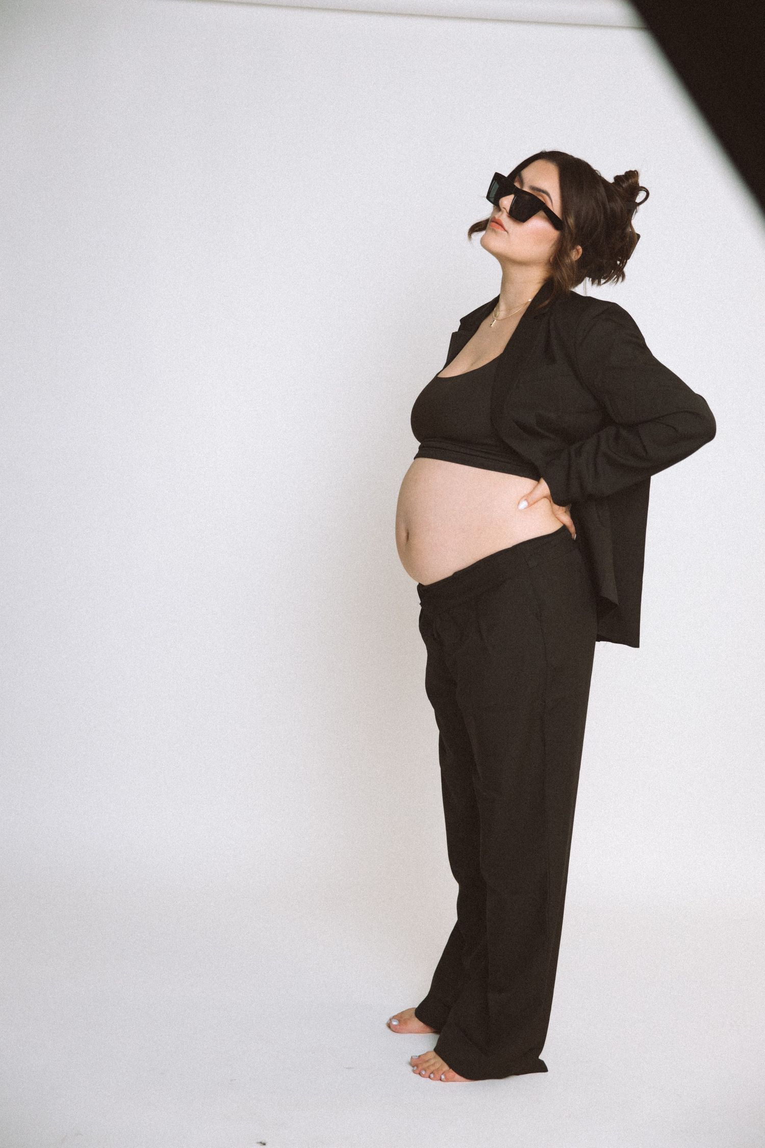 Maternity fashion photo with expecting model in black suit and sunglasses.
