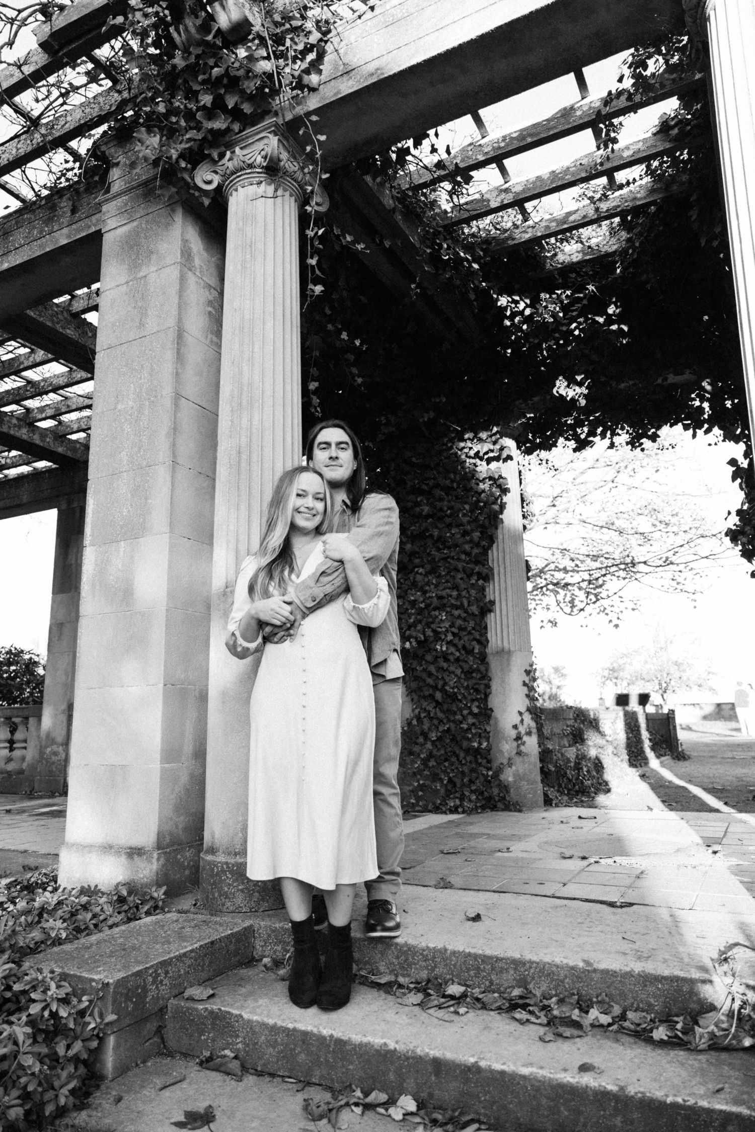 Black and white photo series showing a couple posing playfully around classical columns.