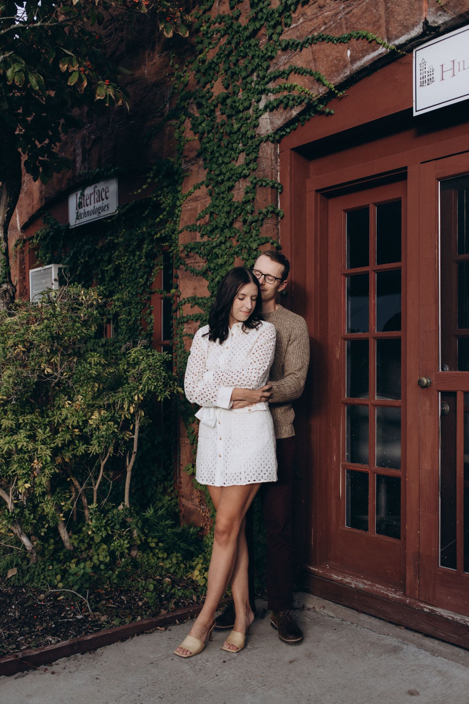 Romantic couple photos against a brick building with ivy and windows.