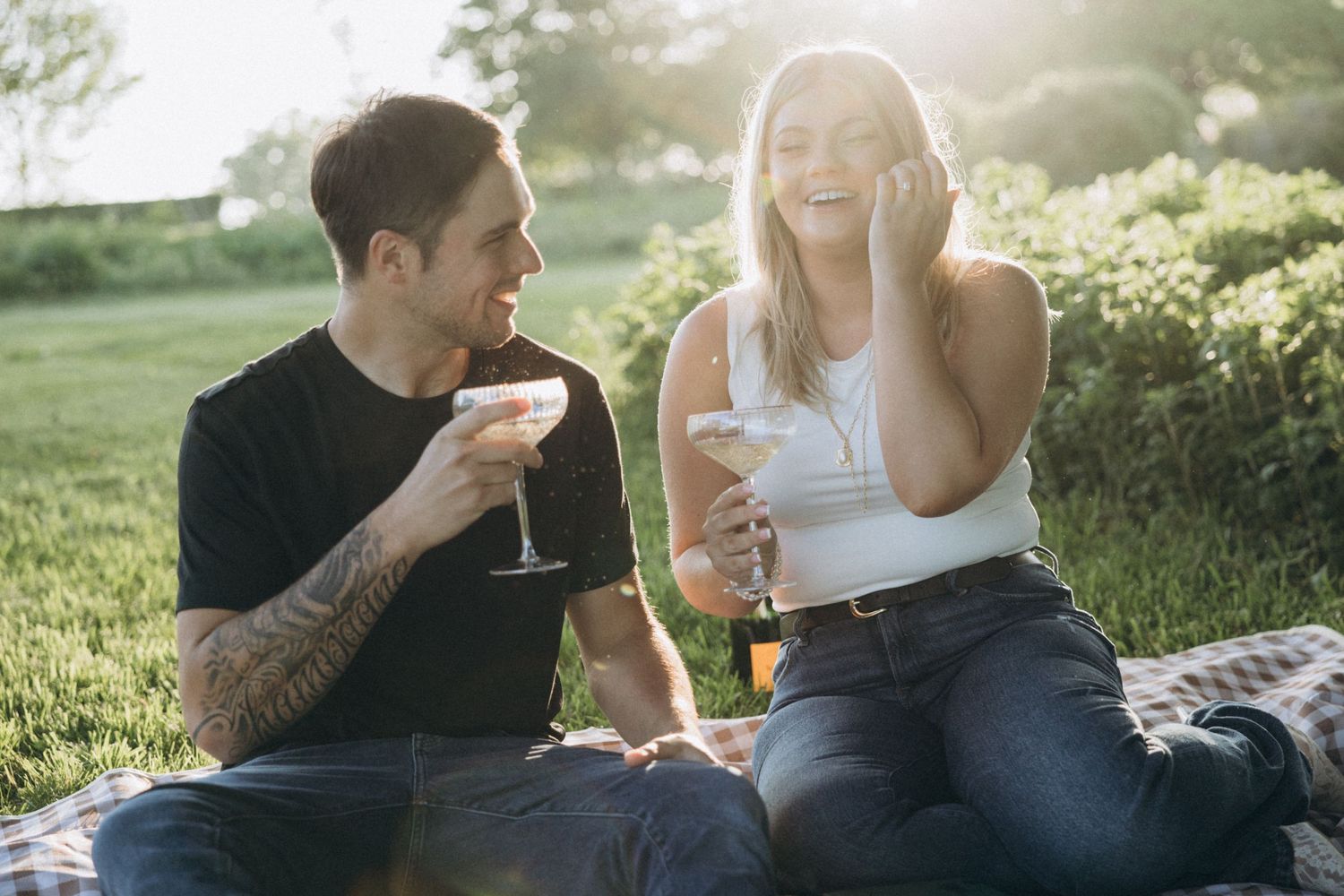 A couple enjoys wine together on a sunny afternoon picnic.