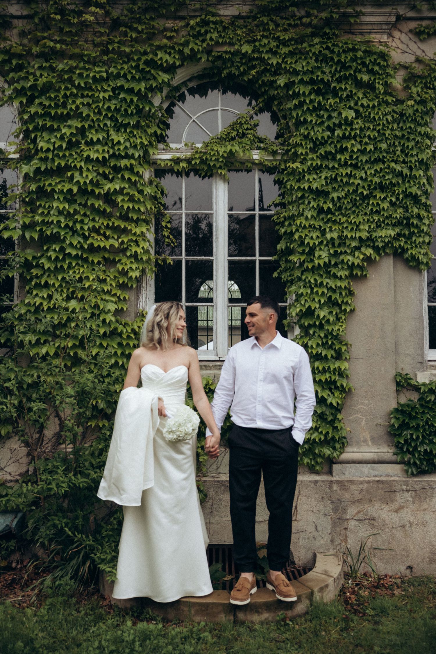 Wedding portraits against ivy-covered wall of historic building.