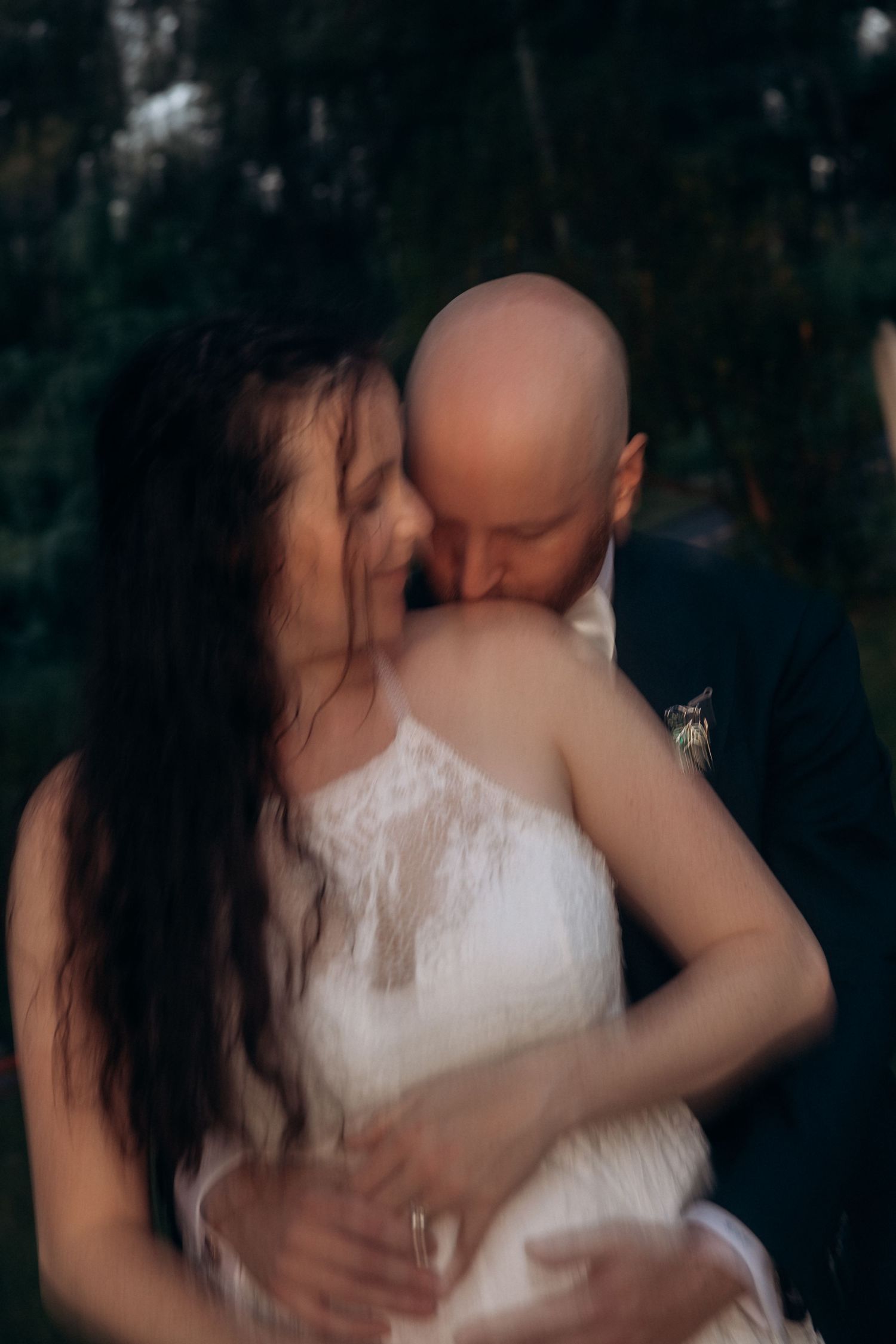 Intimate embracing moment between newlyweds during outdoor wedding celebration.