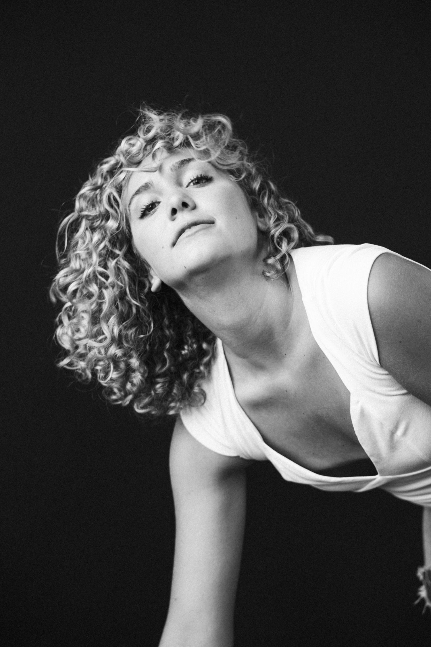 Dramatic black and white series with dynamic poses in white top against dark background.
