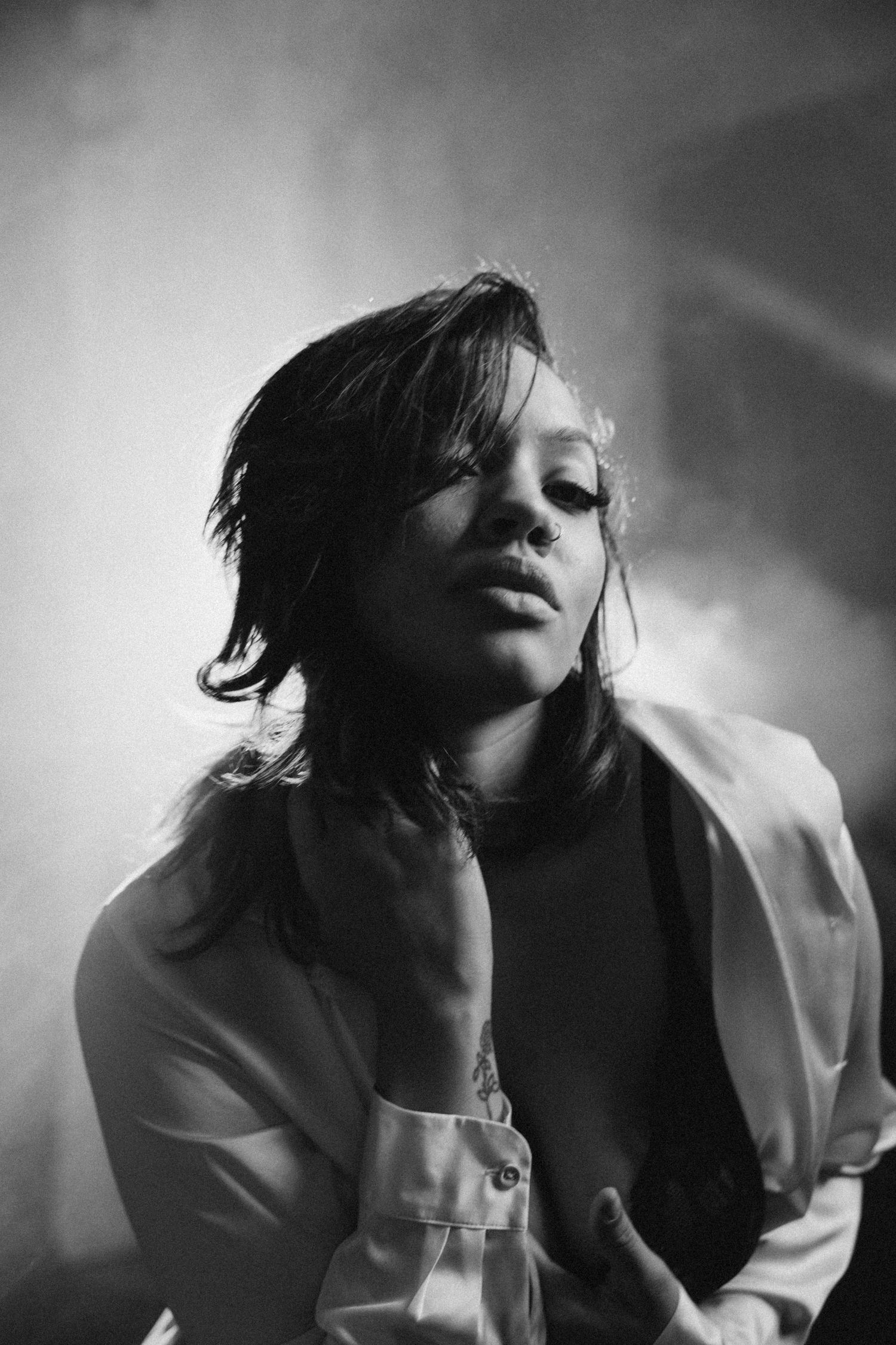 Artistic black and white portrait with dramatic lighting and white blazer.