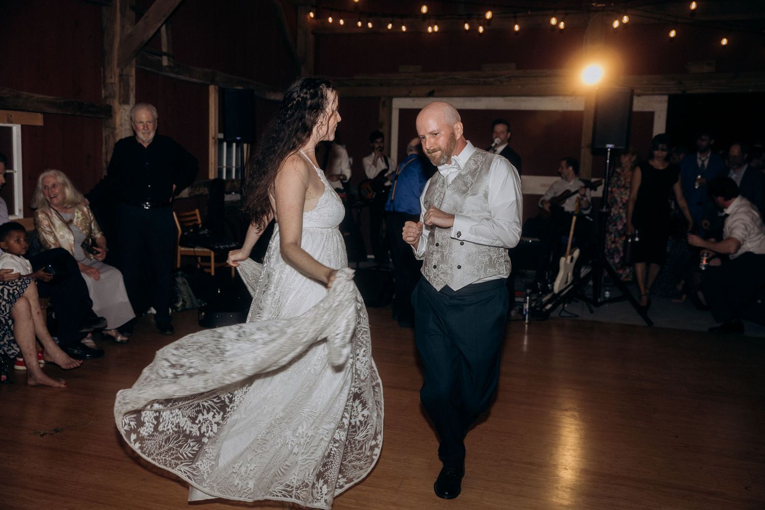 Newlyweds dancing together in a dimly lit reception venue with decorative lighting.