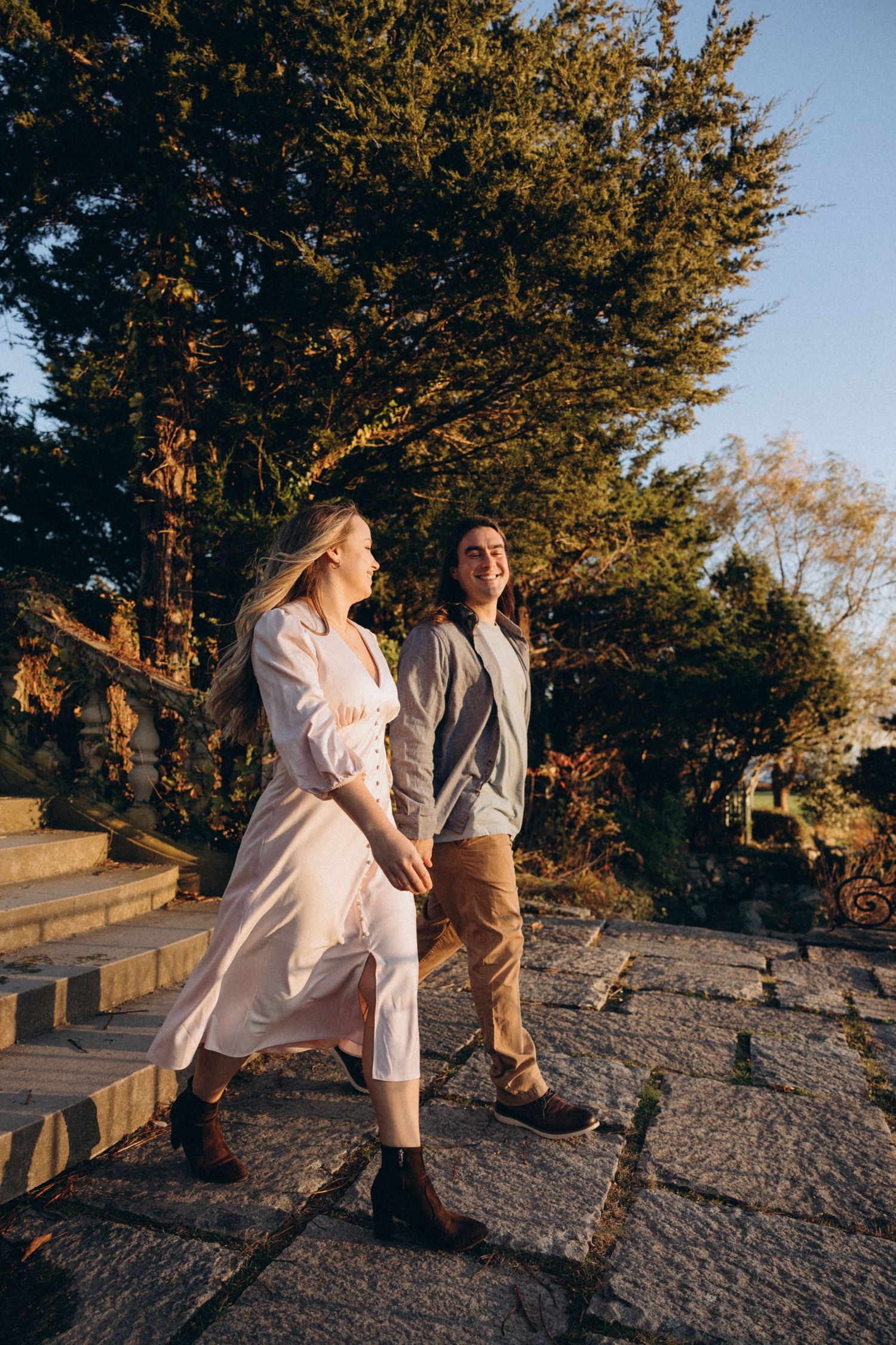 A carefree couple enjoys a sunny moment on stone steps surrounded by autumn trees.