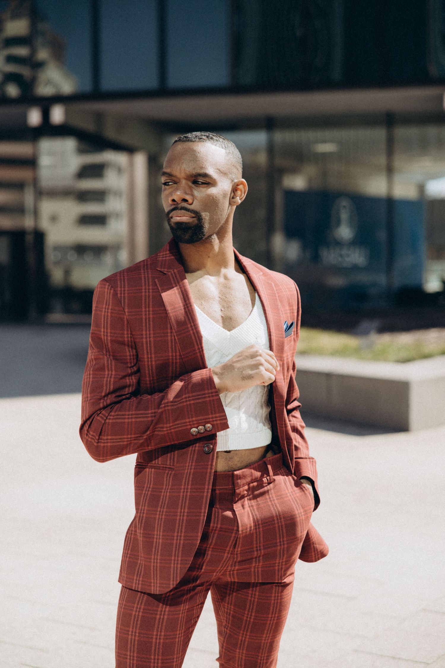 Fashion editorial showcasing a red plaid suit in an urban setting with dynamic poses.