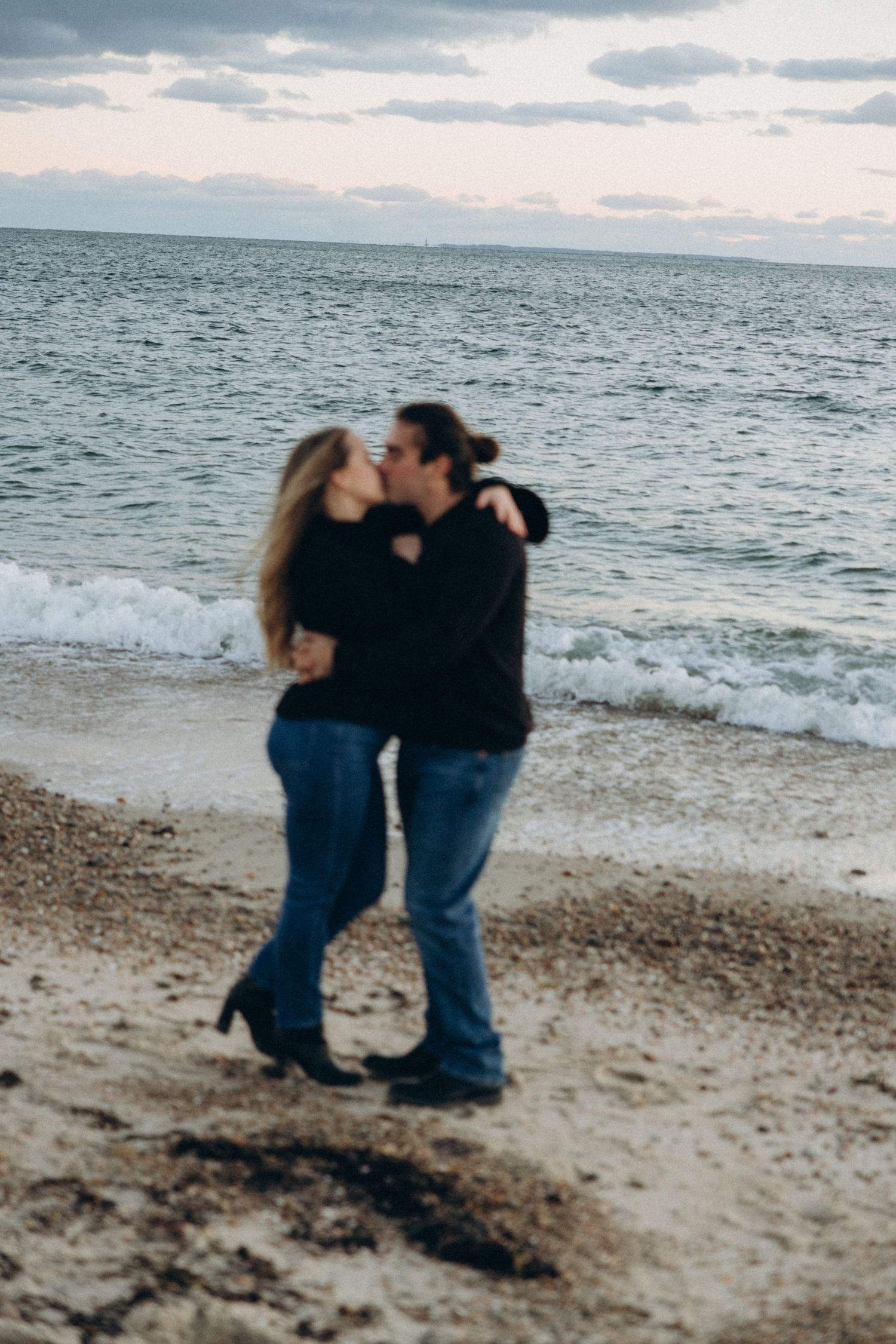 A romantic couple shares an intimate moment together walking along a beach at sunset.